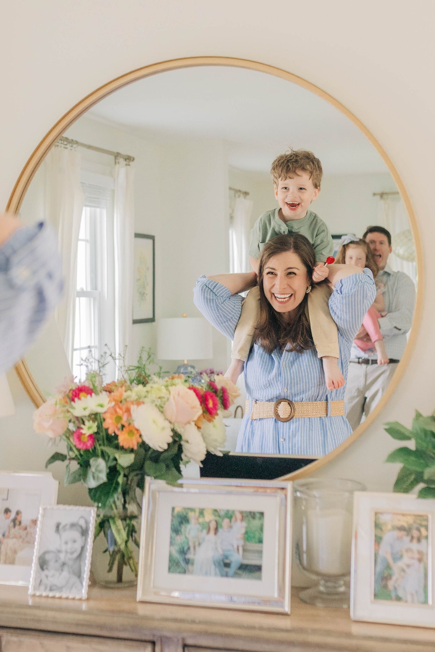 Cheerful scene reflected in a round mirror with floral decor and family photos.