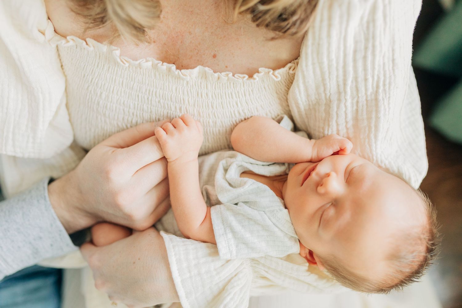 Tender moment between parents and infant as they cuddle together on white bedding.