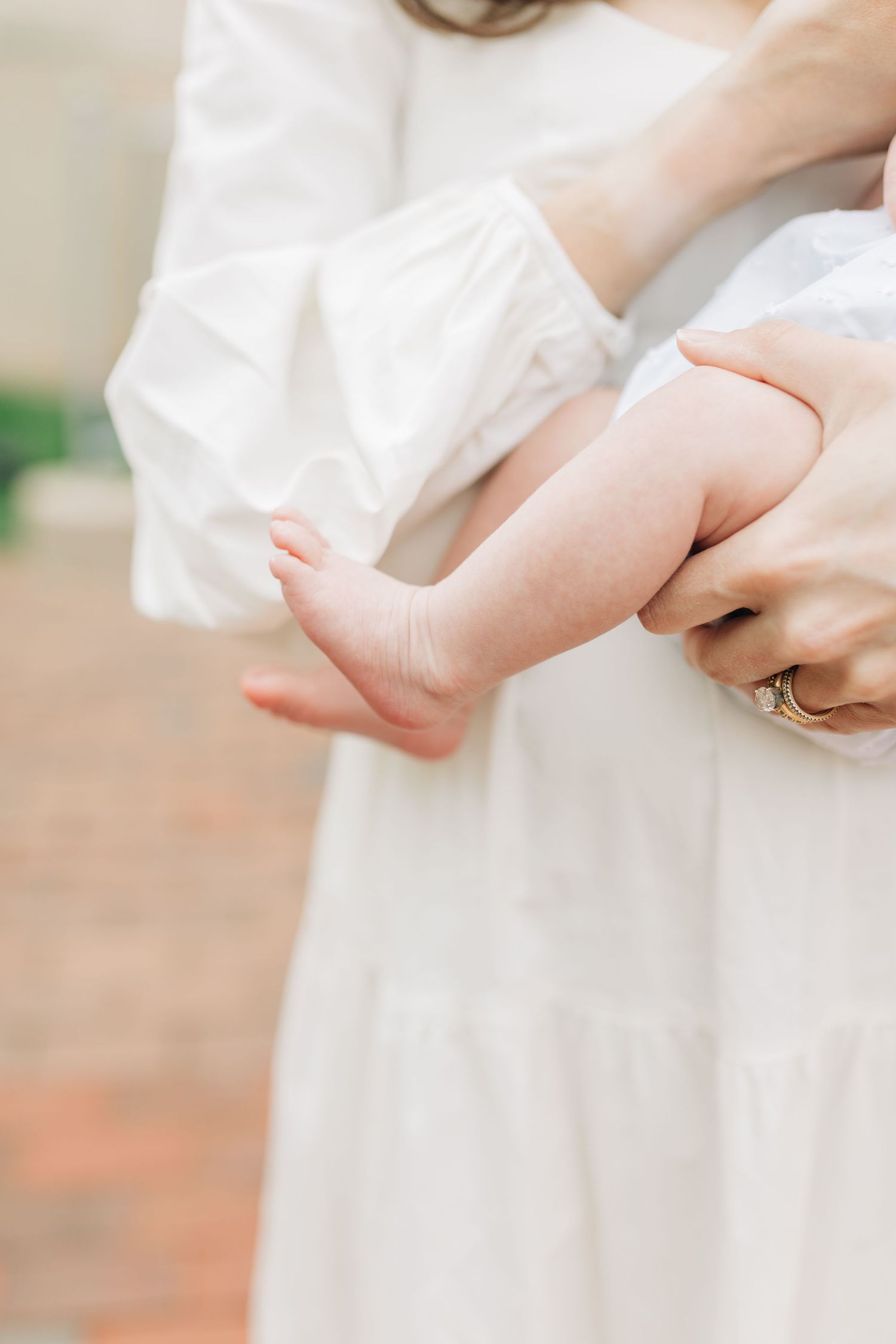 Close-up details of a white dress and hands holding a baby.