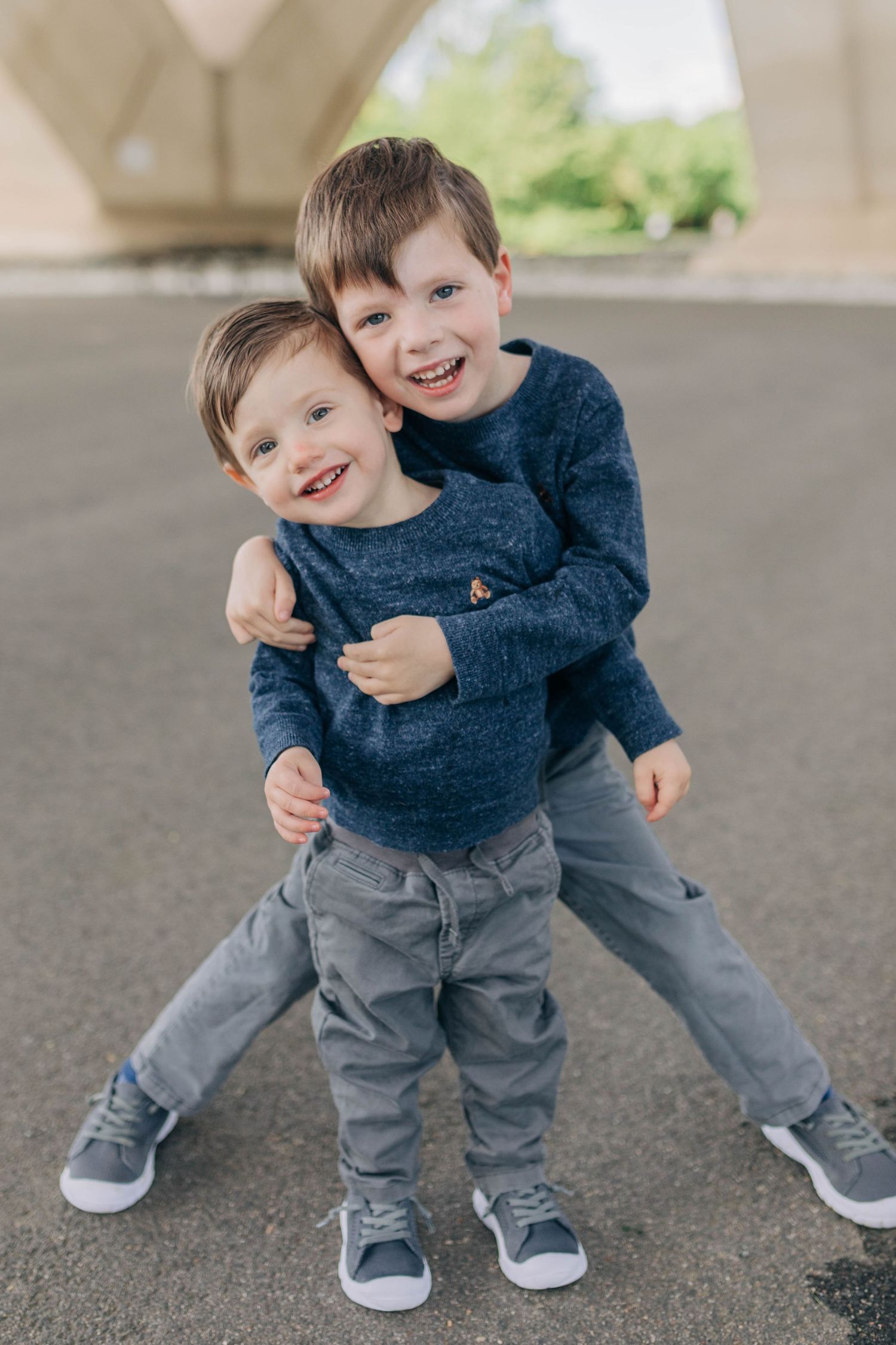 Children playing and laughing together under urban concrete structure.