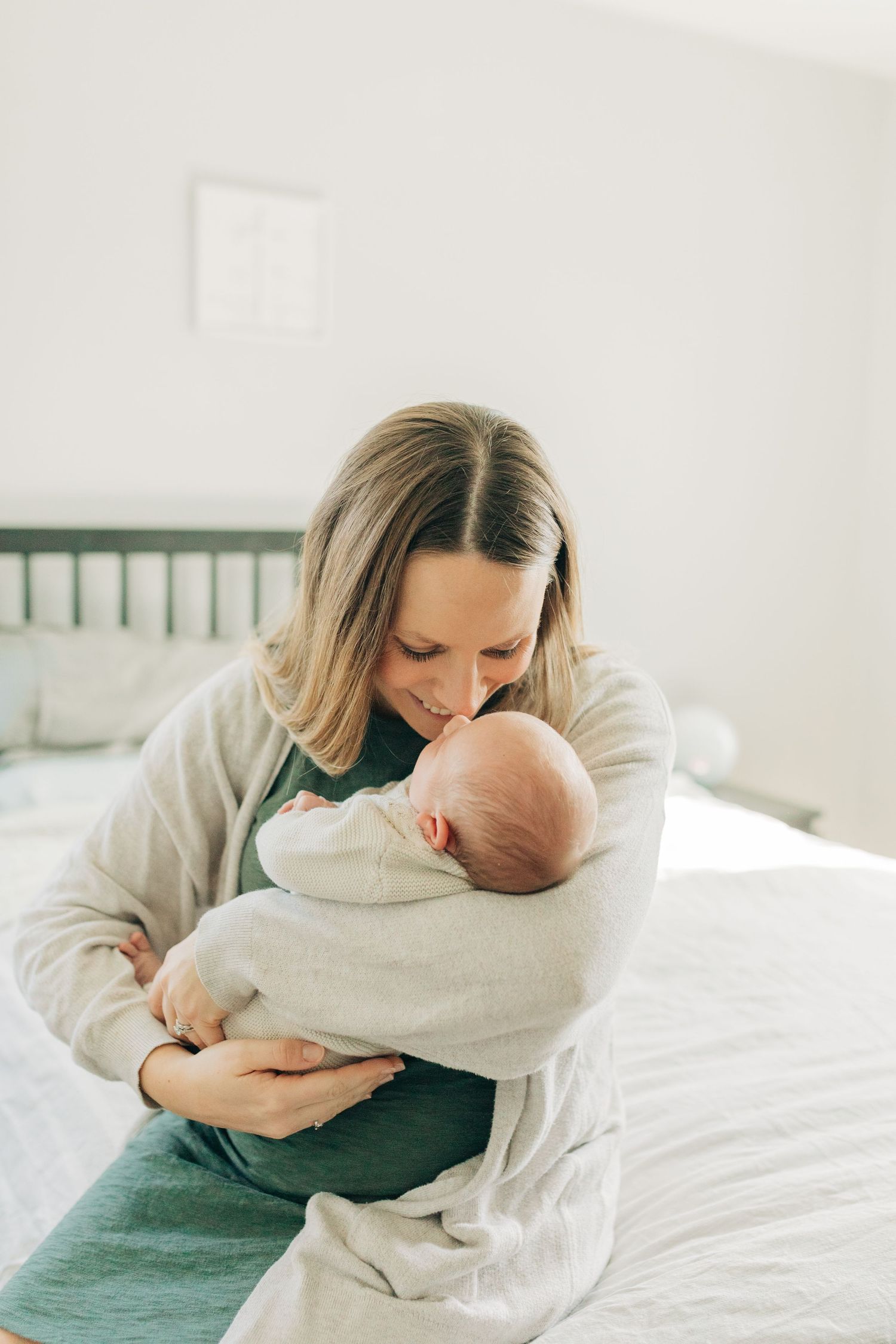Intimate bonding moment with a newborn baby swaddled in soft white fabric on a bed.