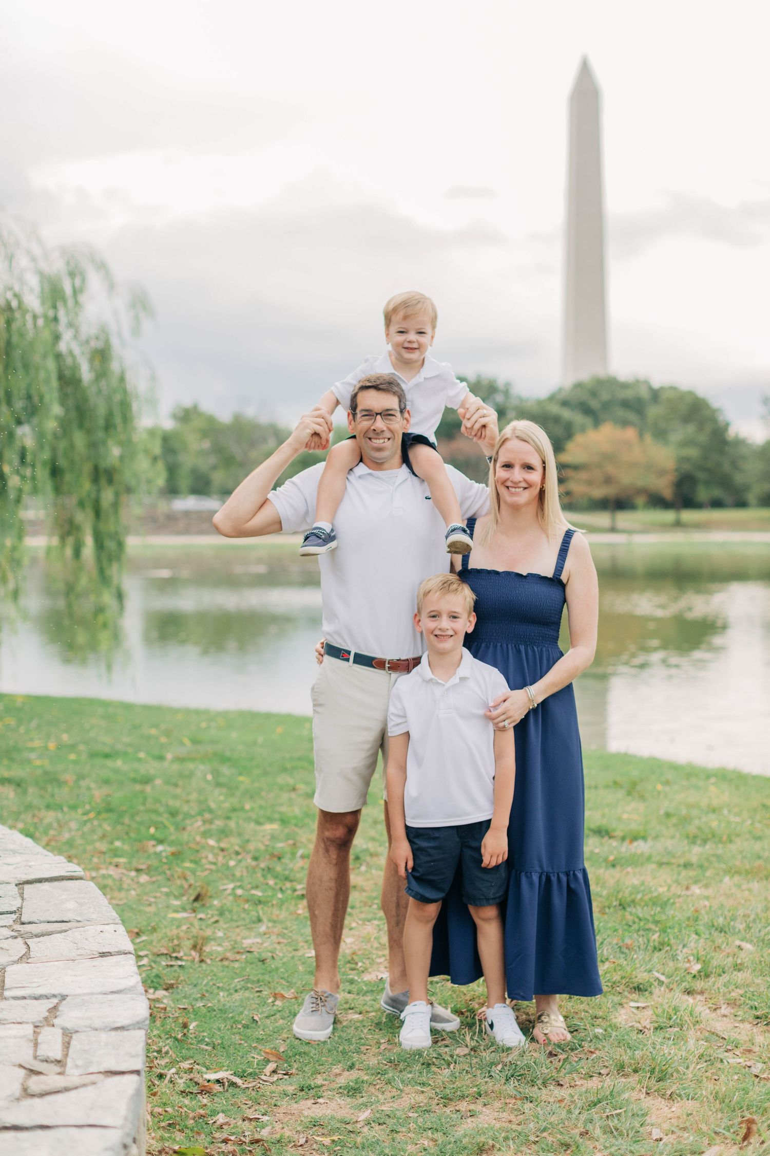 A family poses together near the reflecting pool with the Washington Monument in view.