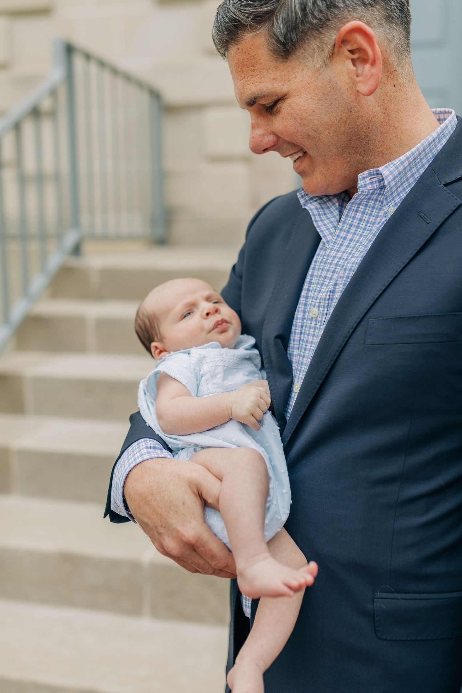 Multiple candid shots showing loving interactions with a newborn baby on stone steps.