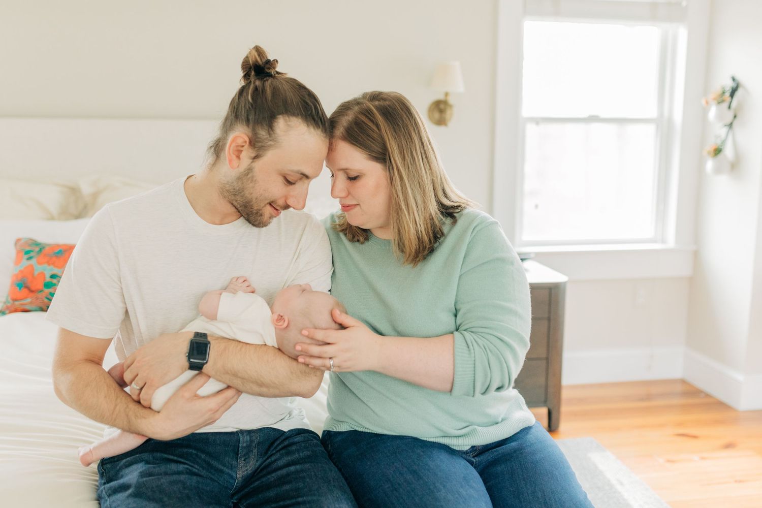 Family sharing tender moments together in a bright, modern bedroom setting.