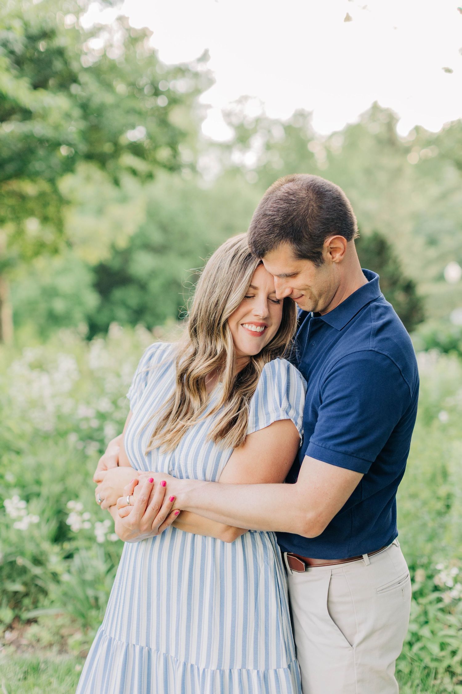 A couple shares tender moments in a garden setting wearing blue and white striped outfits.