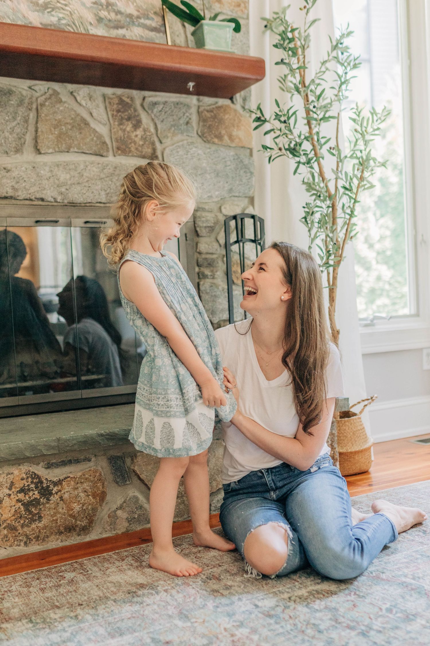 Joyful moments captured on a patterned rug near a stone fireplace in a sunlit room.