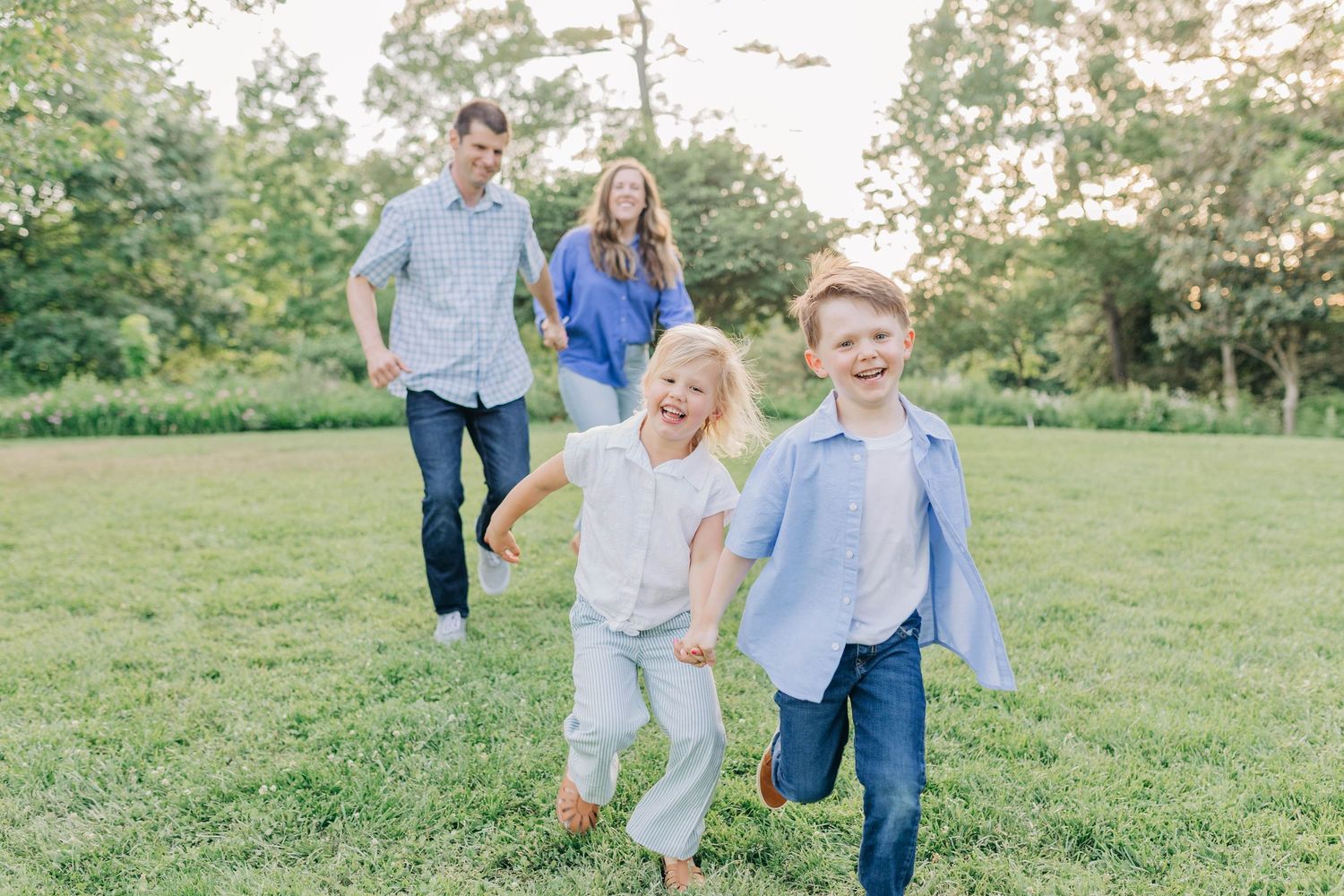 Playful family moments photographed in a sunlit meadow during golden hour.