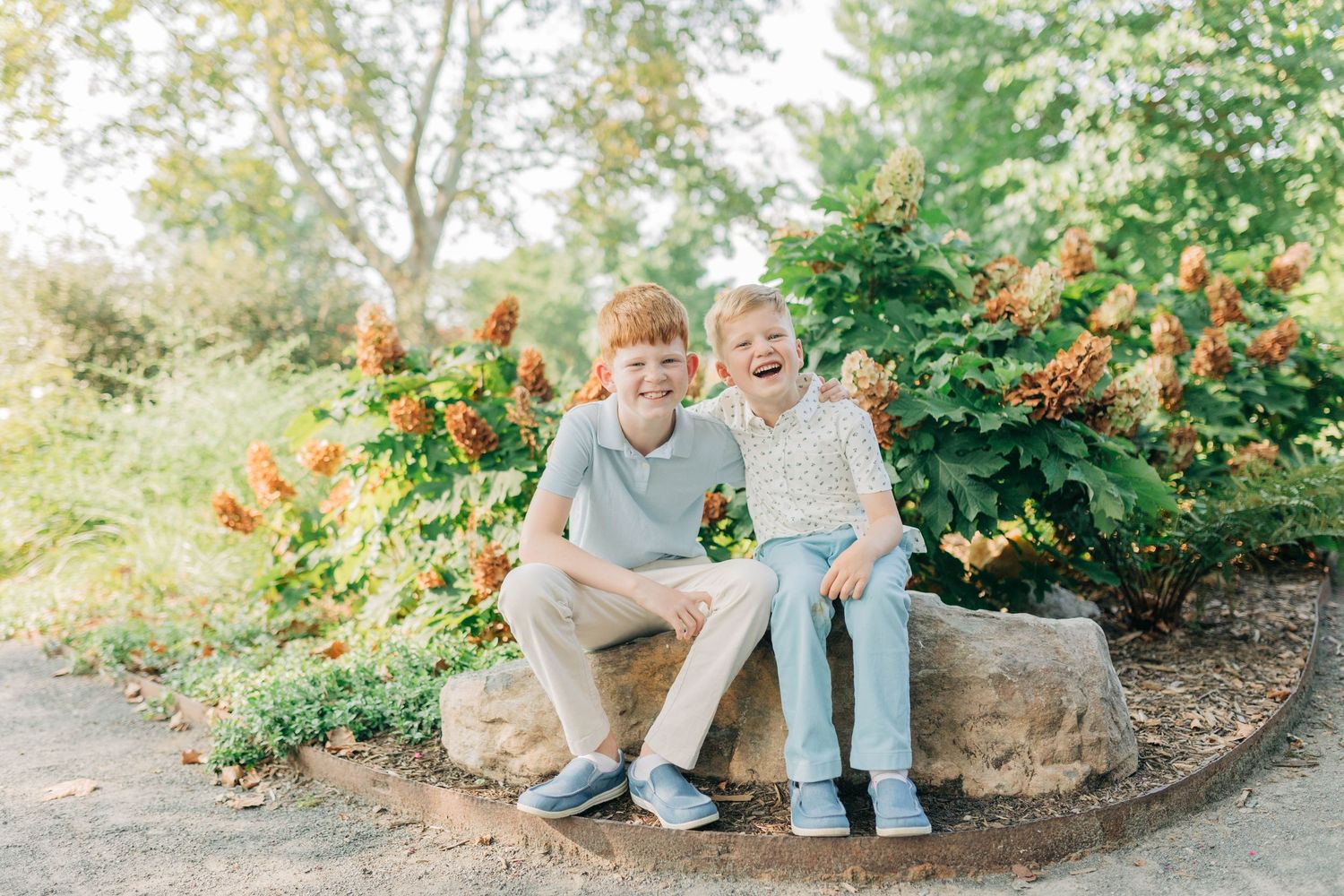 Garden photography session featuring stone landscaping and flowering trees in background.