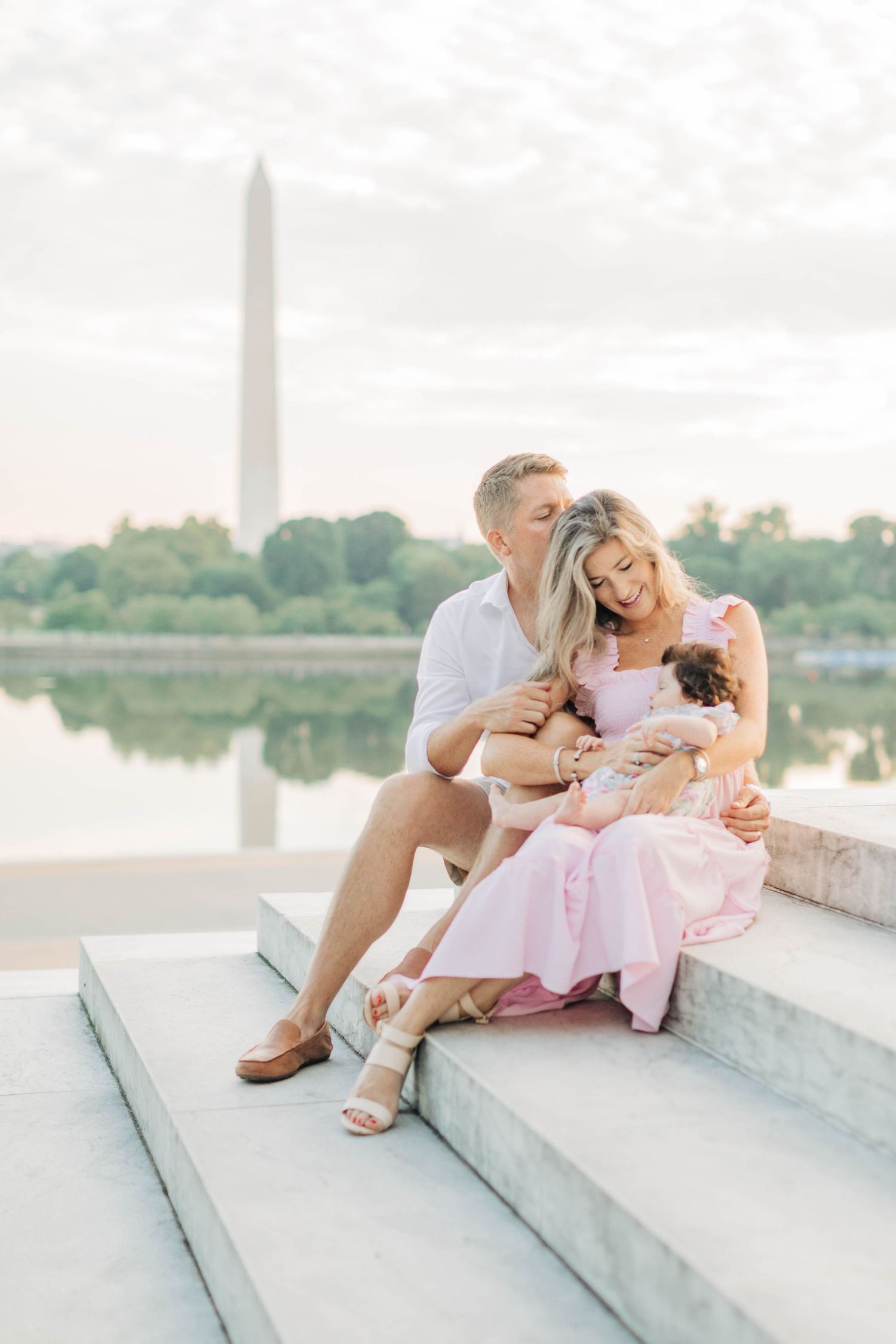 Family relaxing together on marble steps near the Washington Monument at sunset.