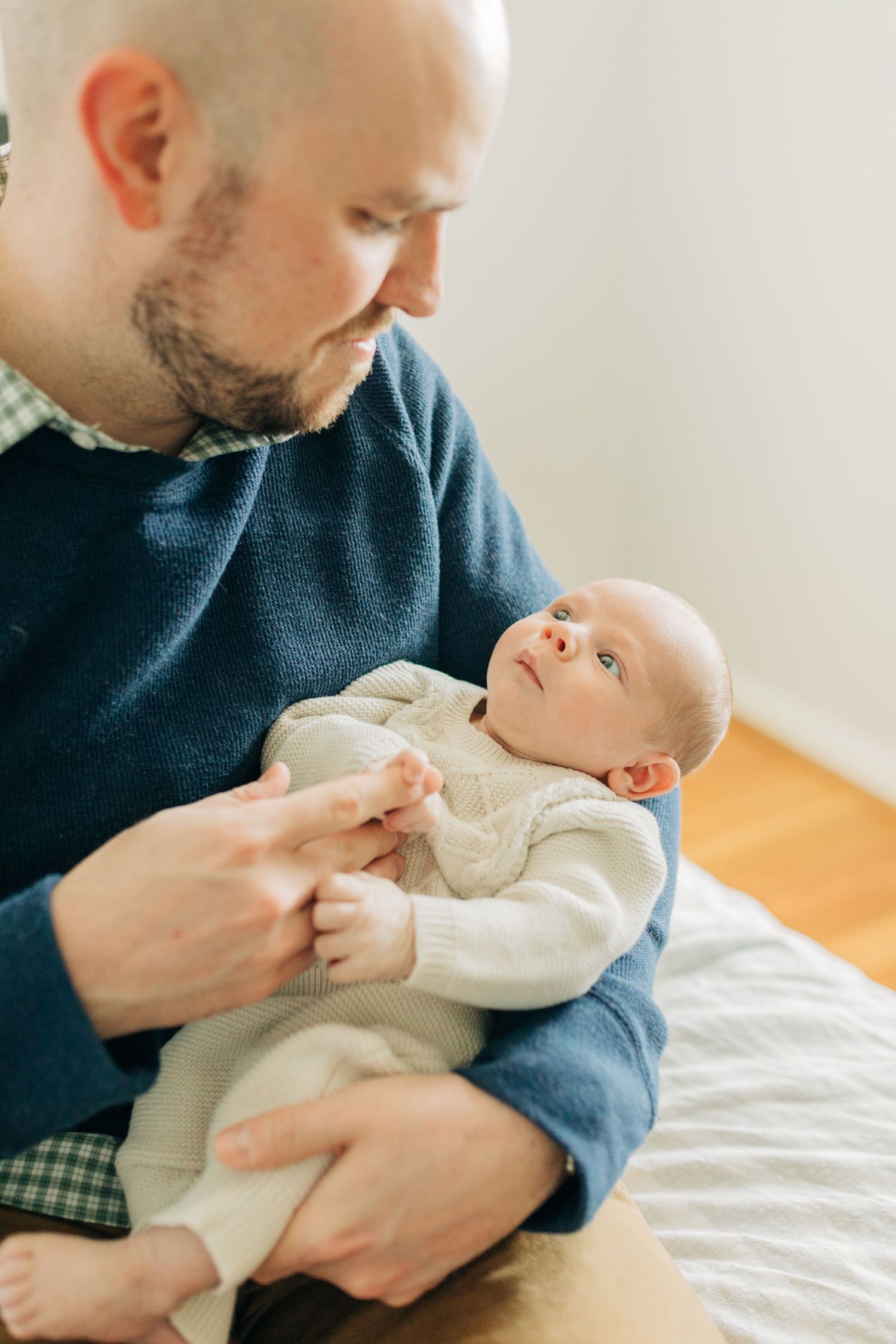 Intimate moments of parent holding and feeding newborn baby in cream-colored outfit.