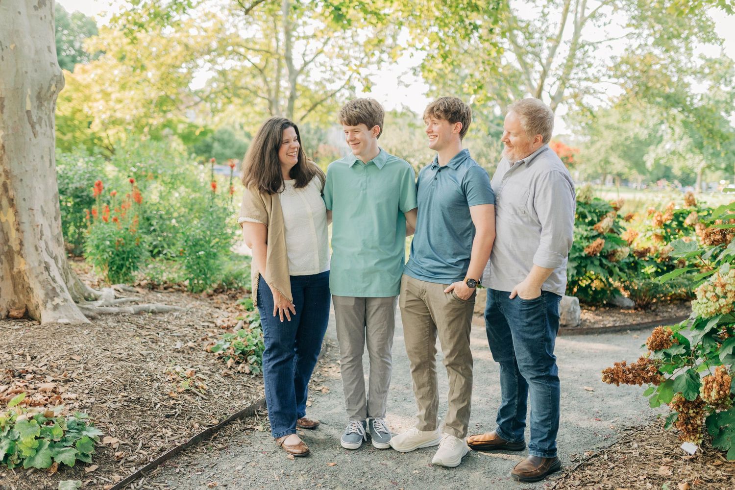 Extended family gathering outdoors for casual group photo in natural setting.