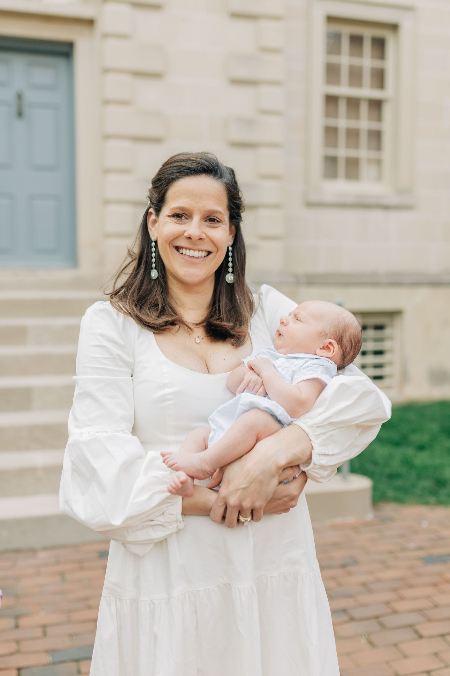 A sweet moment between parent and infant on brick steps of a historic building.