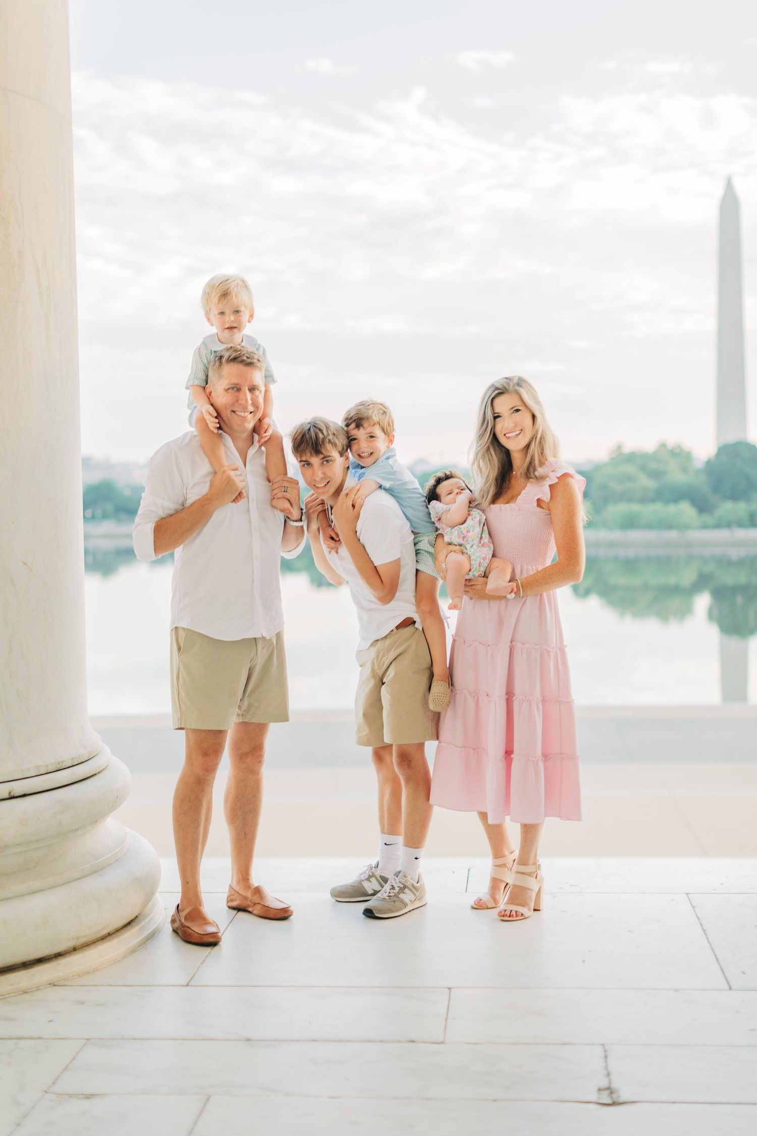 Family portrait at the Jefferson Memorial with the Washington Monument visible across the water.