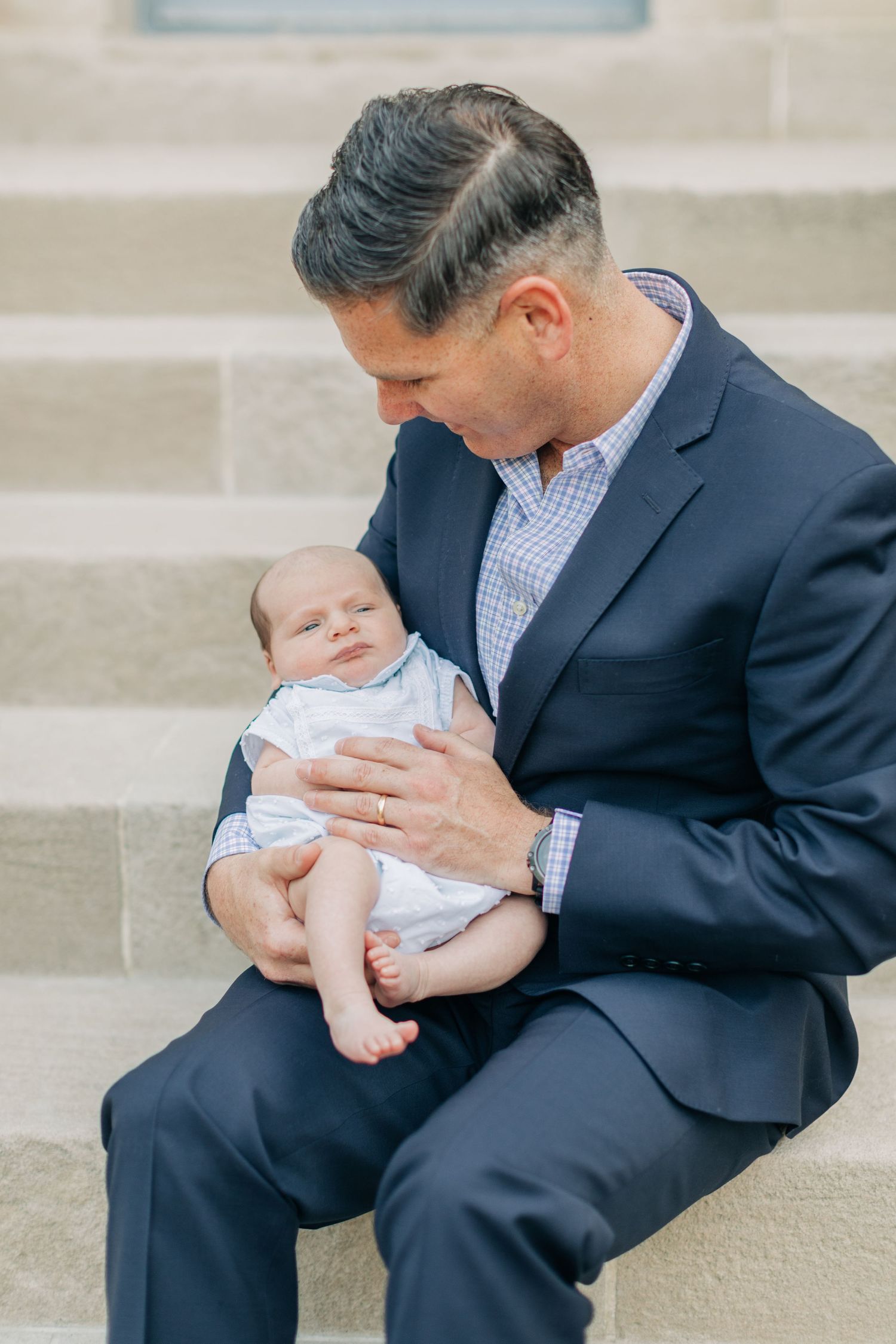 Close-up shots of a person in a suit holding a small baby.