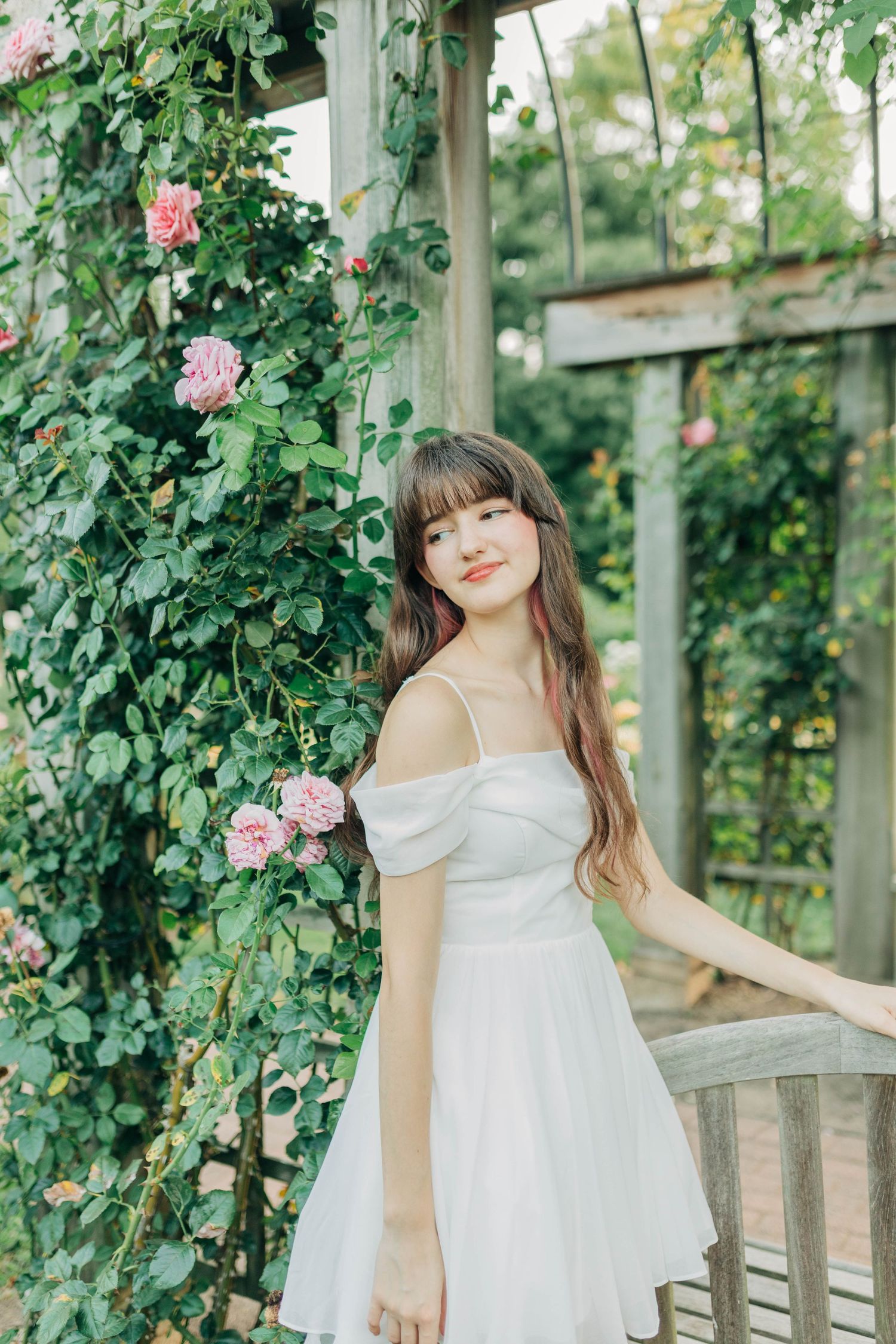 Enchanting garden pergola scene with climbing roses and flowing white summer dress.