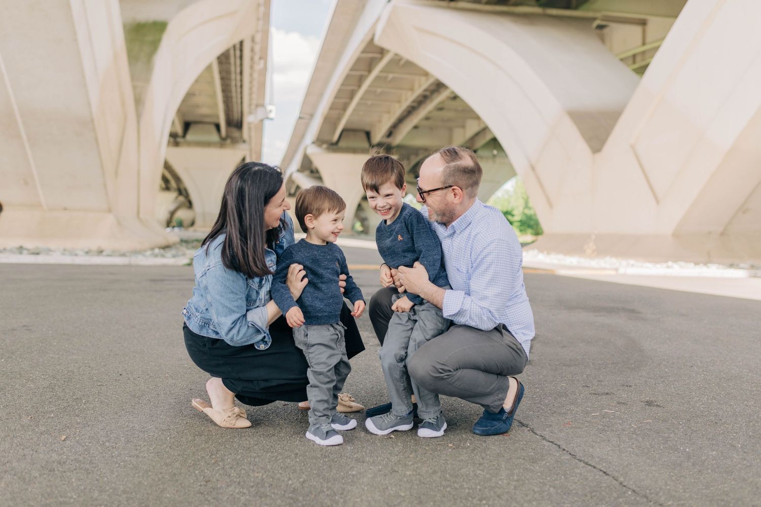 Family members sitting casually together under concrete architectural structure.