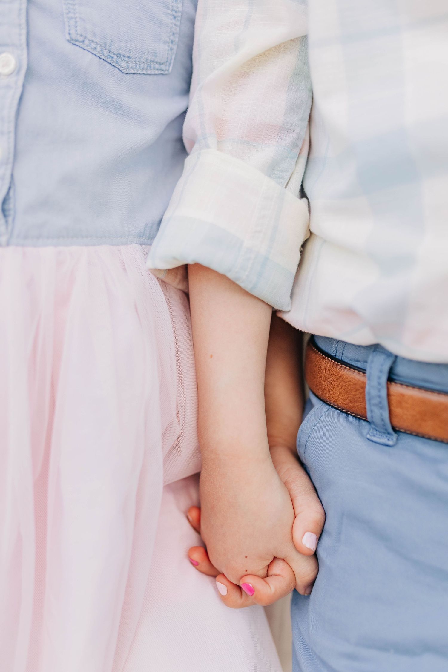 Close-up of children holding hands while wearing coordinating blue and pink outfits.