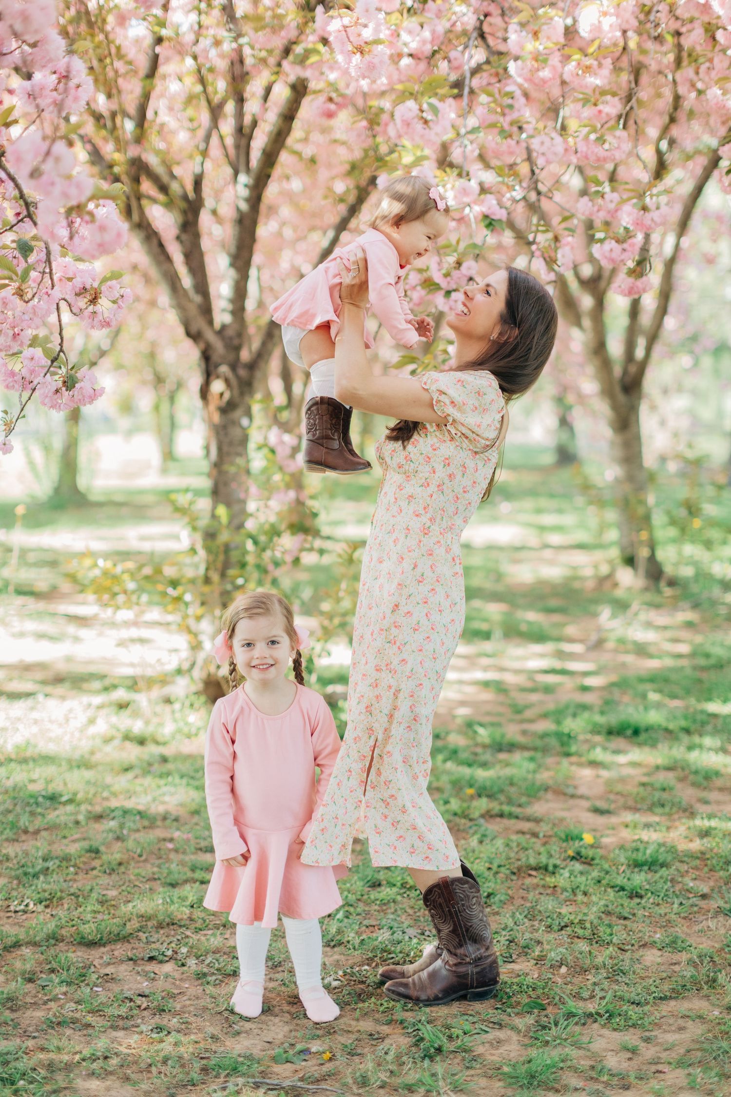 Playing beneath blooming cherry trees in coordinated spring outfits.