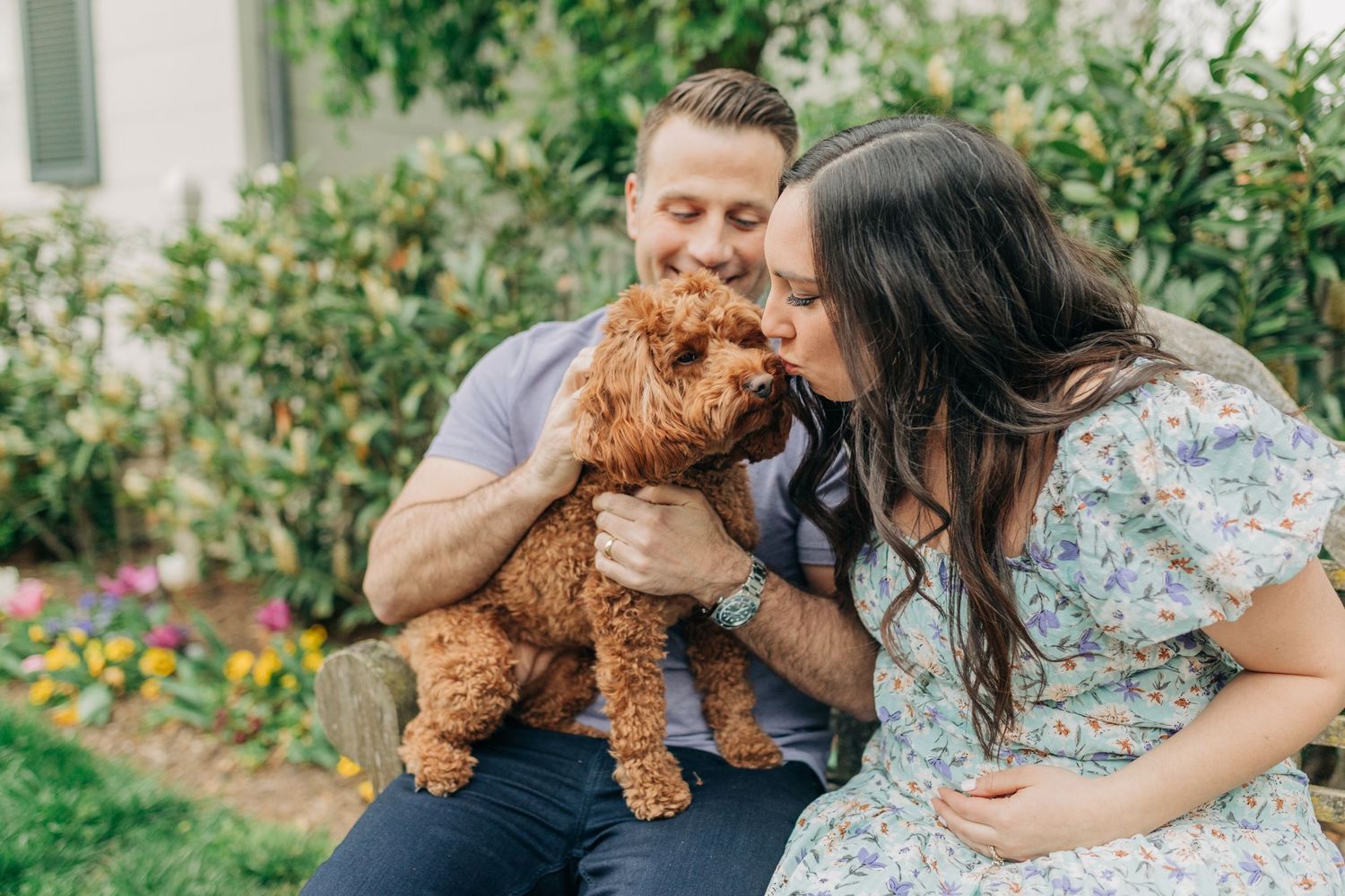 A couple poses with their small brown dog during an outdoor photo session.