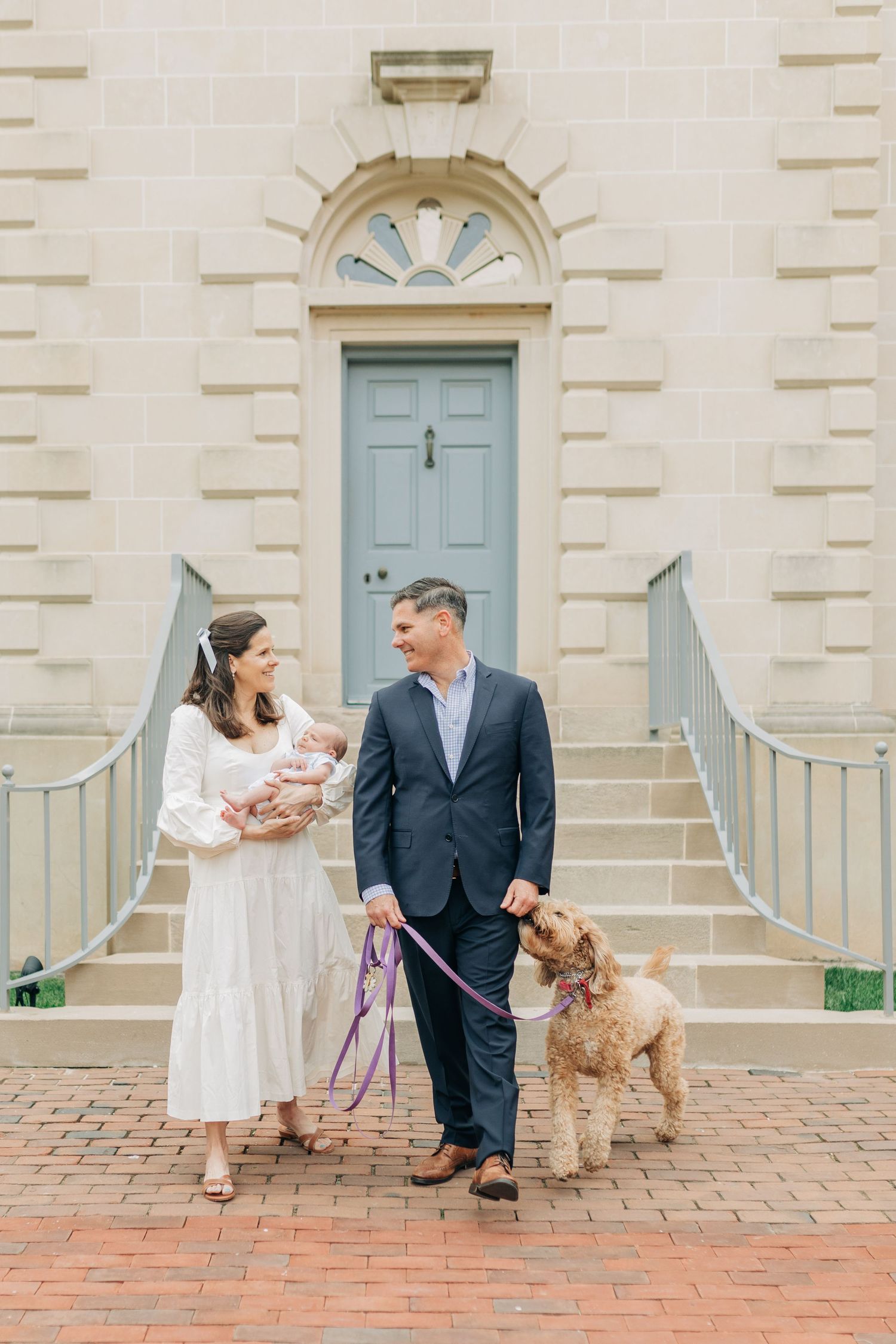 Candid family moment with dog on brick courtyard near blue door.