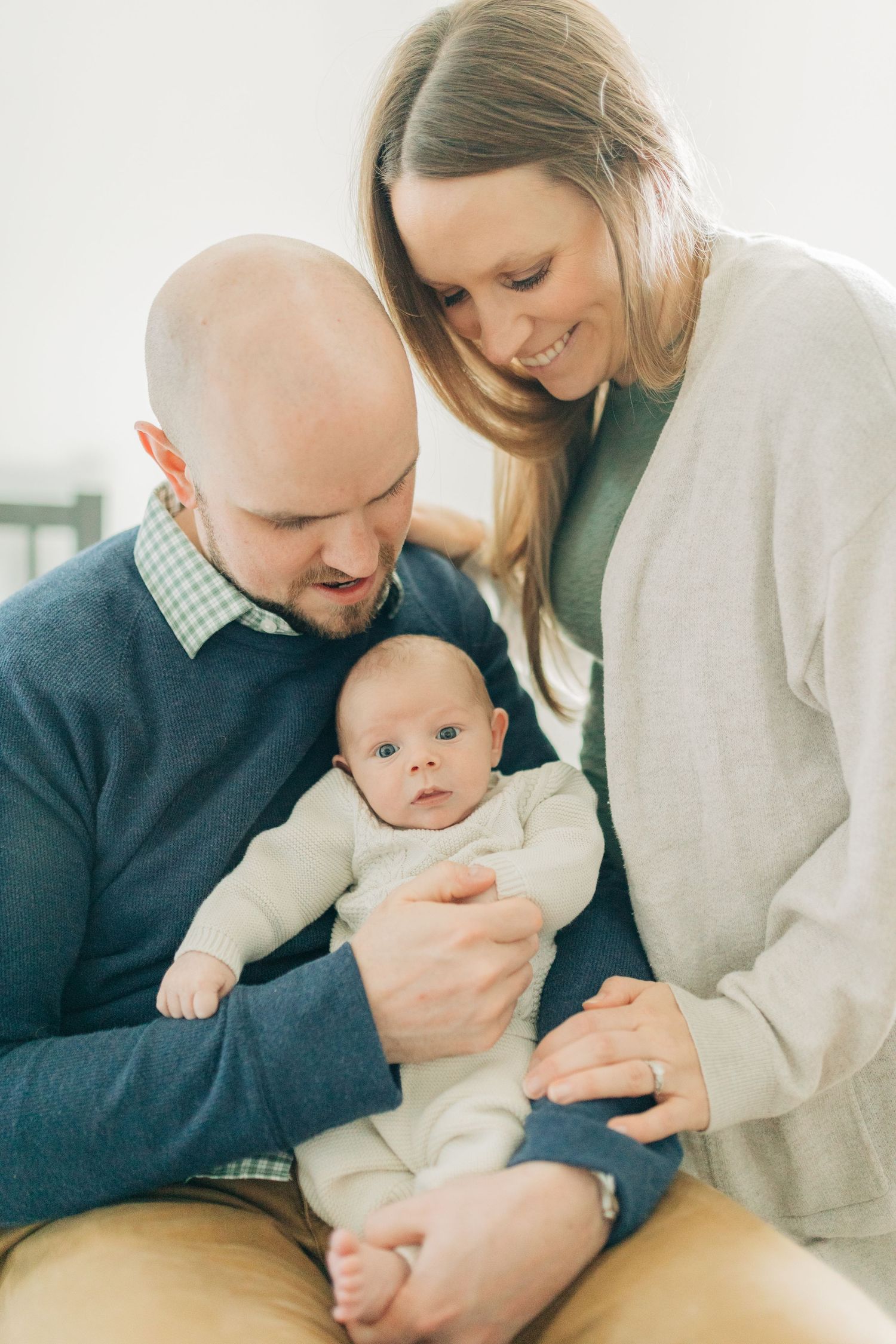 Sweet candid moments of parents gazing lovingly at their baby in a bright room.