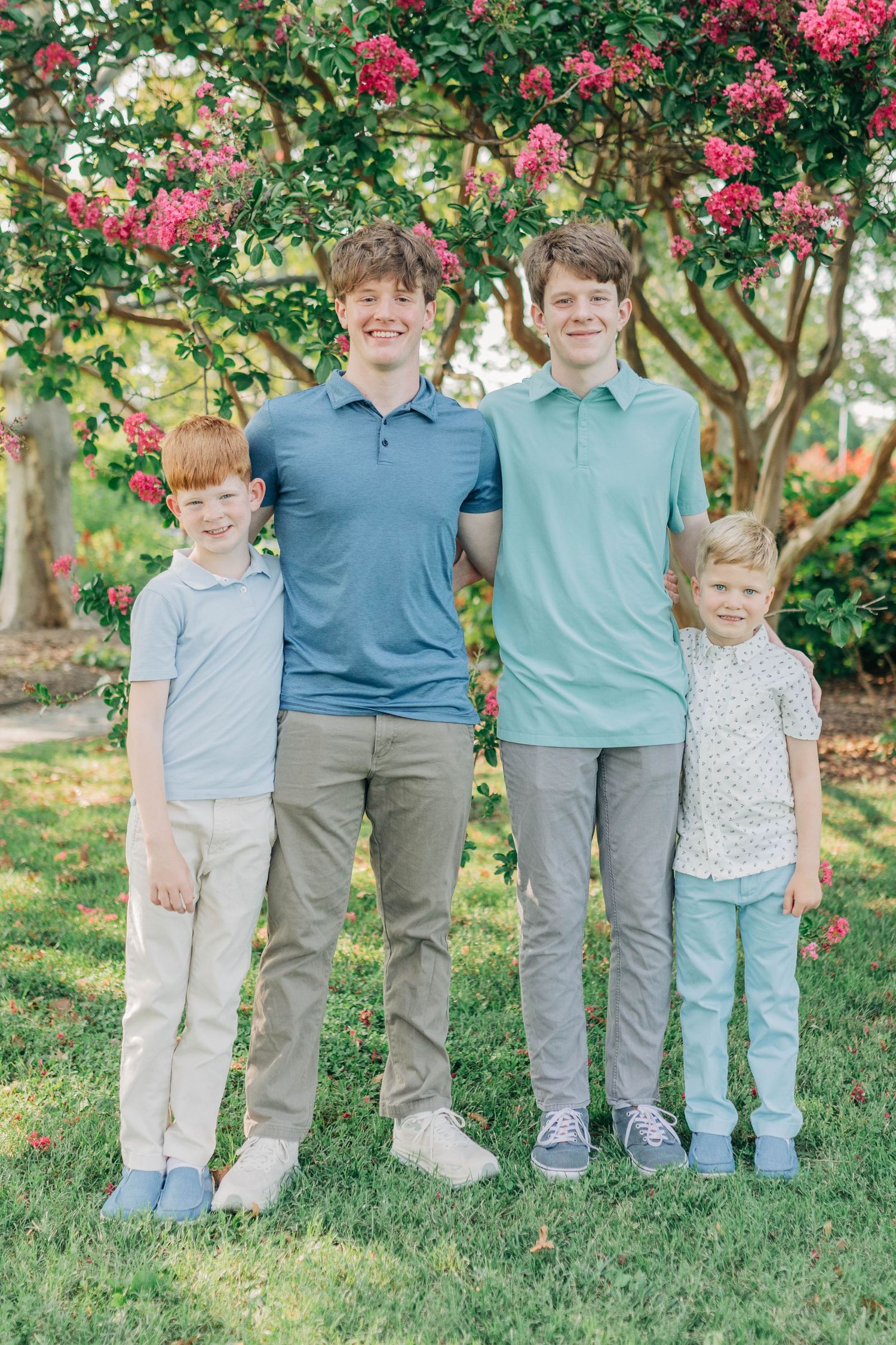 Group portrait of children in coordinating blue and gray outfits standing in a garden.