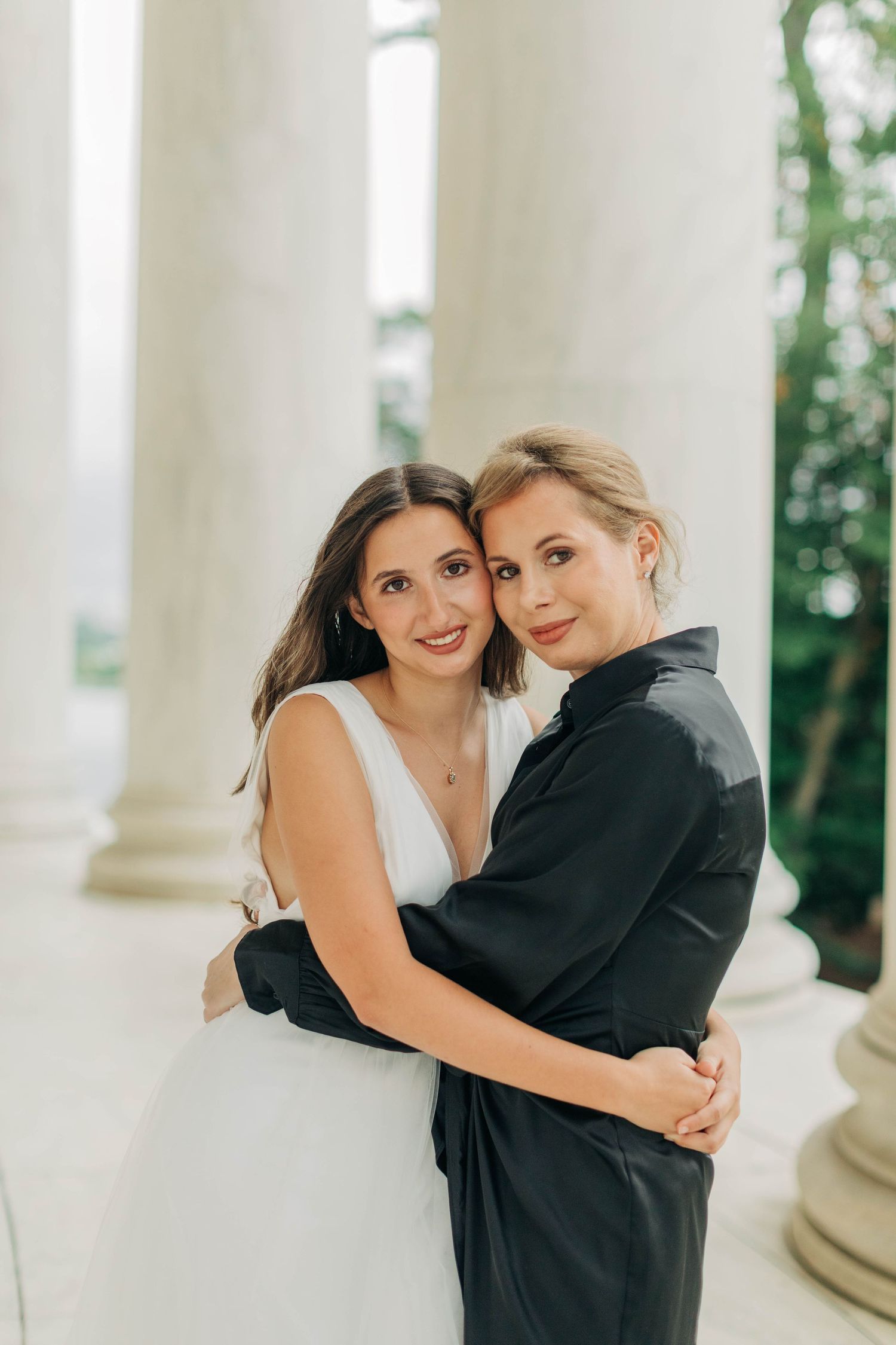 Intimate portrait against white classical columns in formal attire.