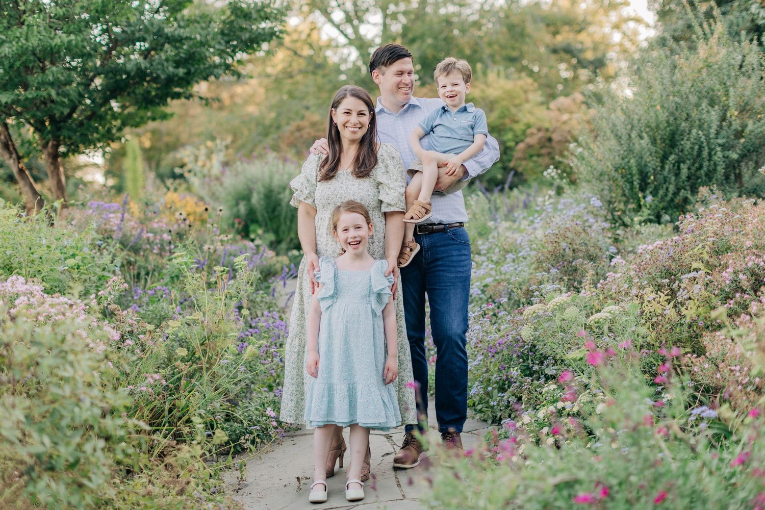 Family portrait in a blooming garden with pink and purple flowers.