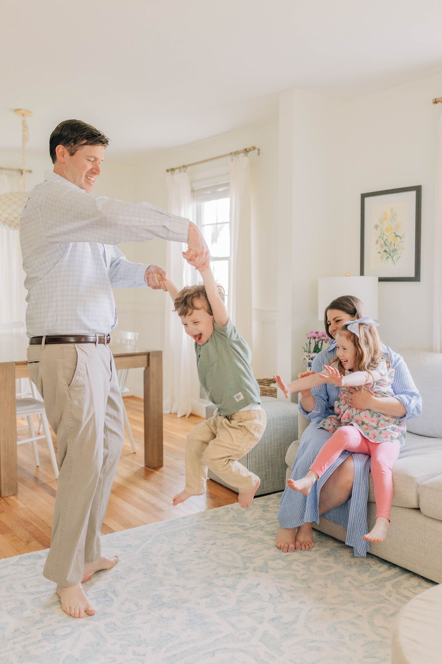 Family playing and jumping together on a white mattress in a sunlit room.