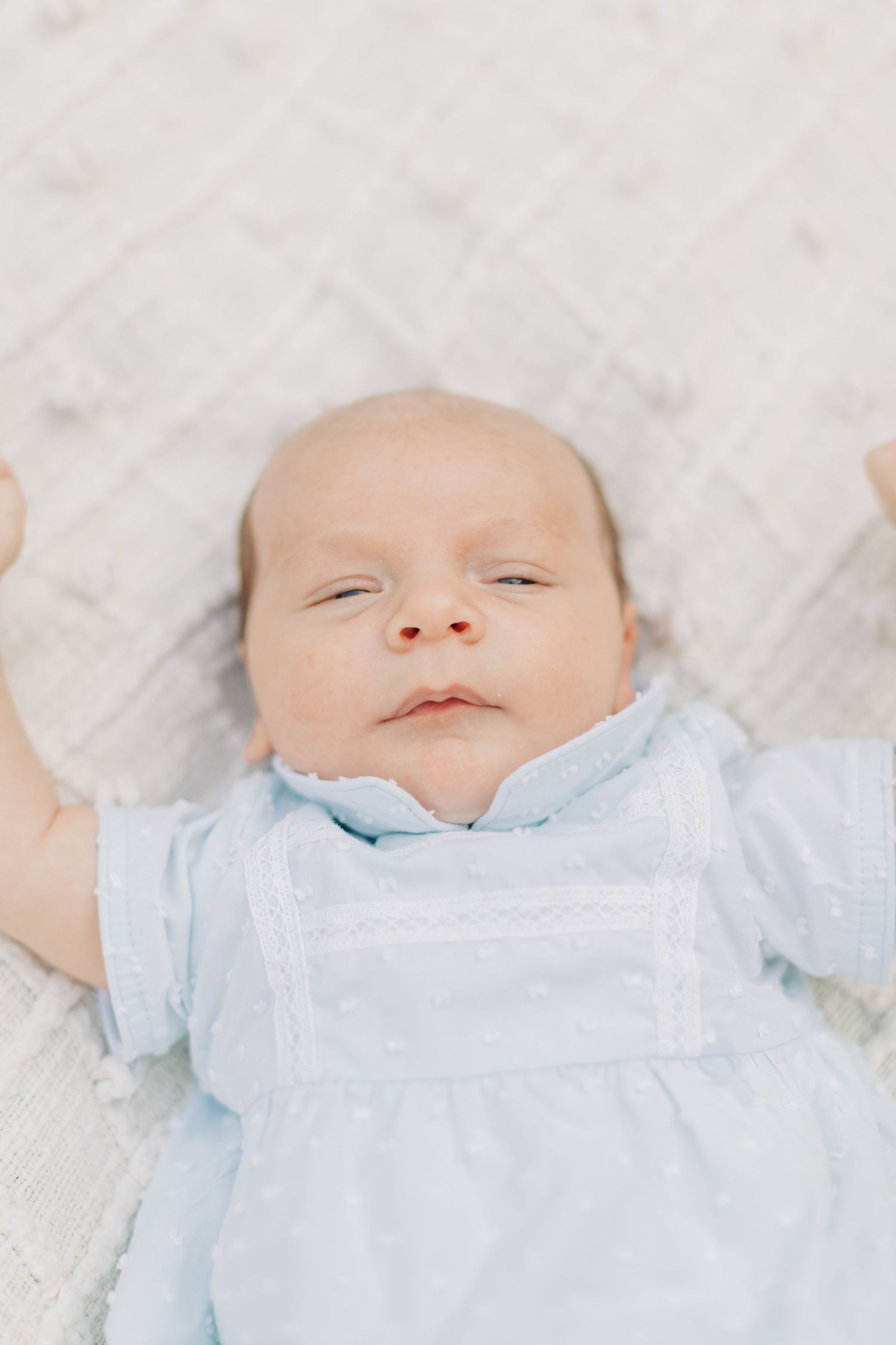 Peaceful sleeping baby in light blue outfit on white textured background.