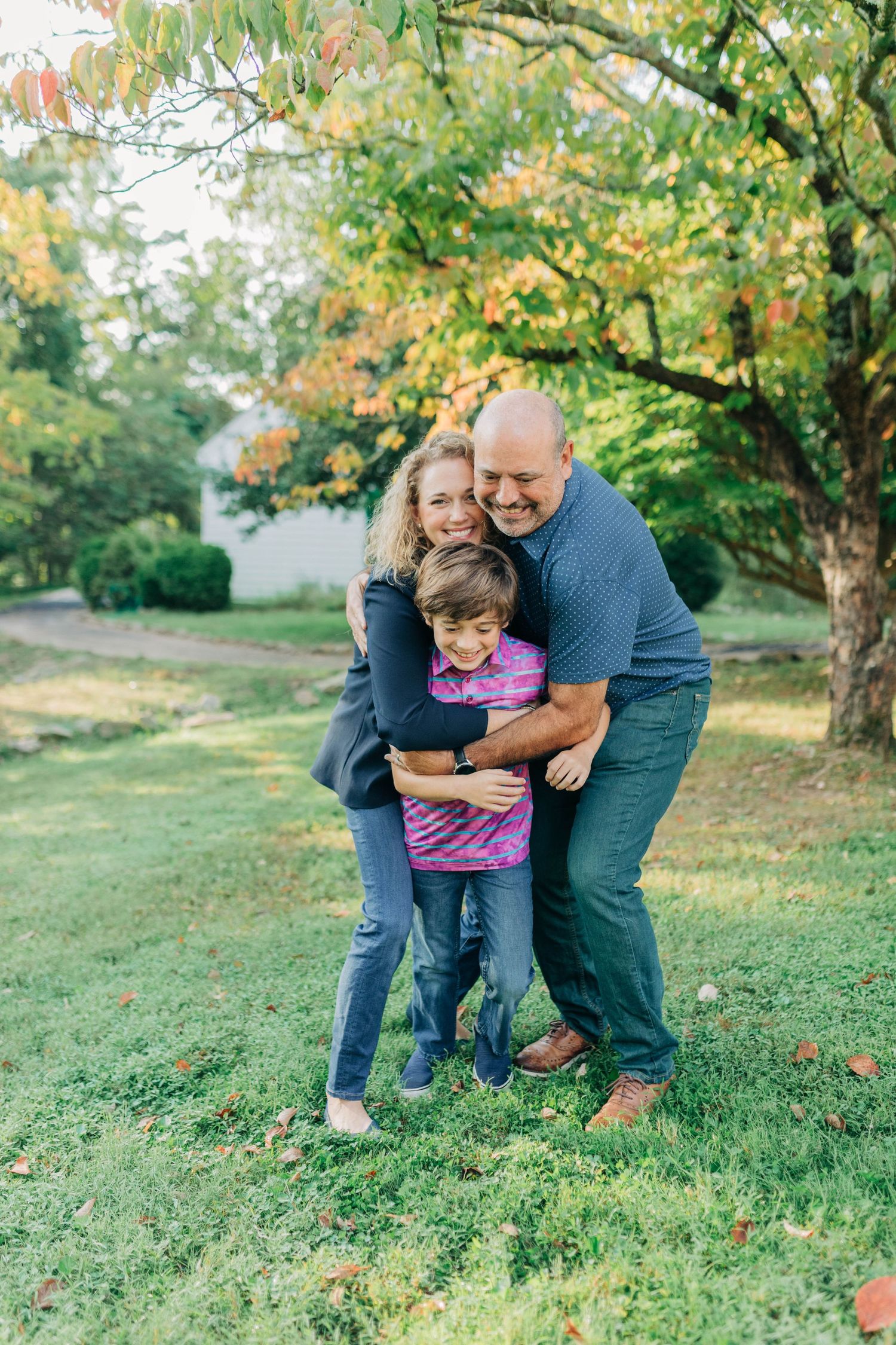 Candid family portrait taken in a park with autumn trees in the background.