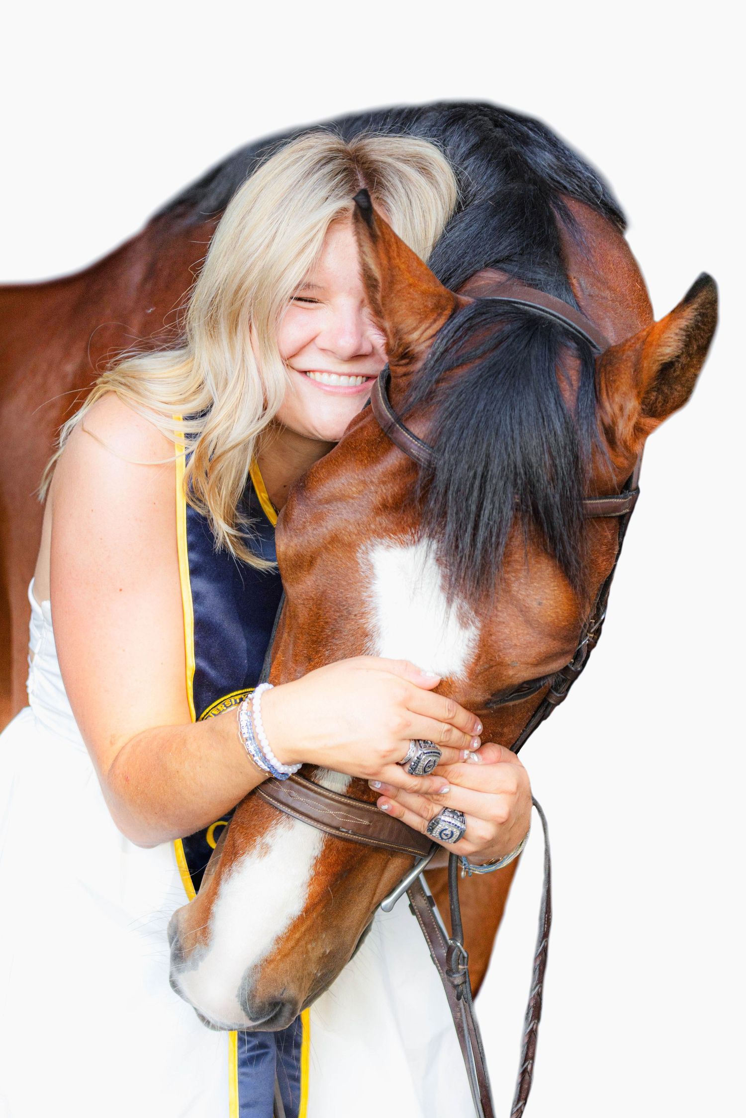 Laughing blonde woman in white dress hugs chestnut horse with white blaze on white background.