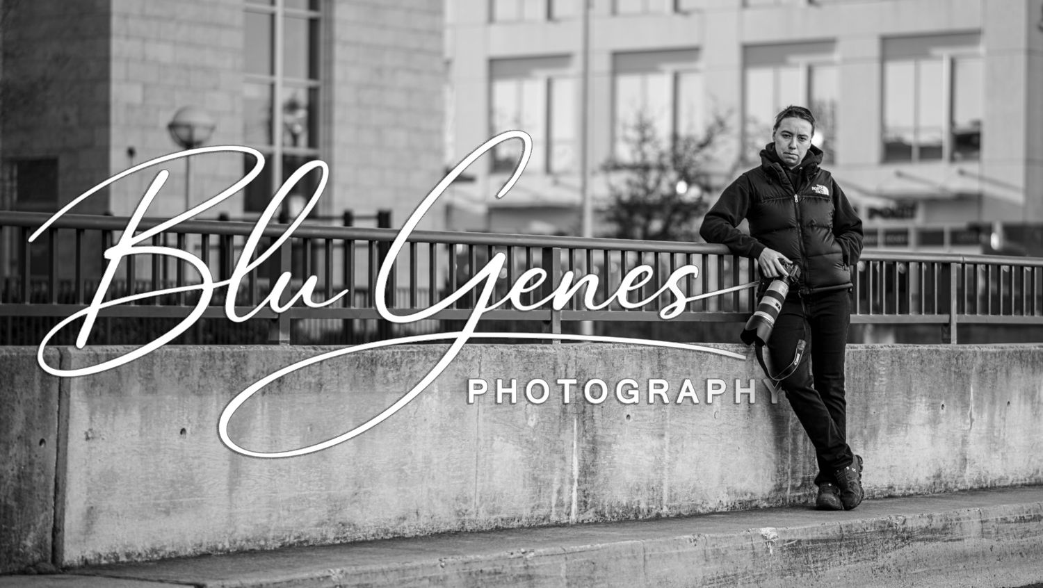Photographer leaning against wall with camera, Blu Genes Photography logo overlay, black and white.