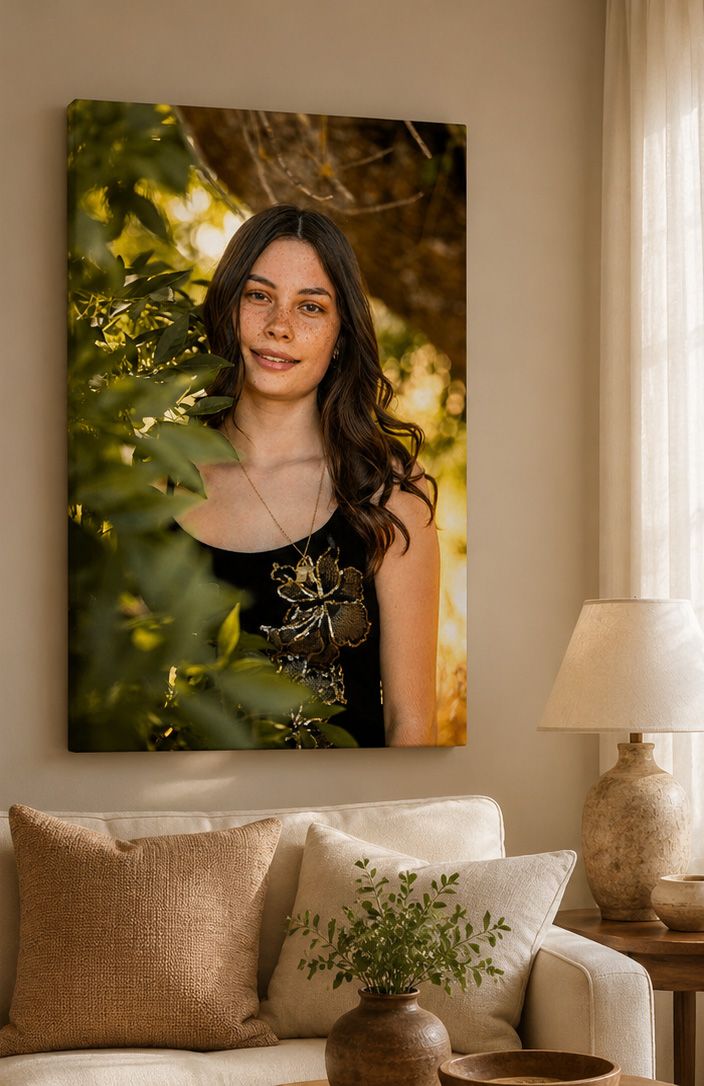 Portrait of a young woman with long dark hair surrounded by green leaves in warm golden light.