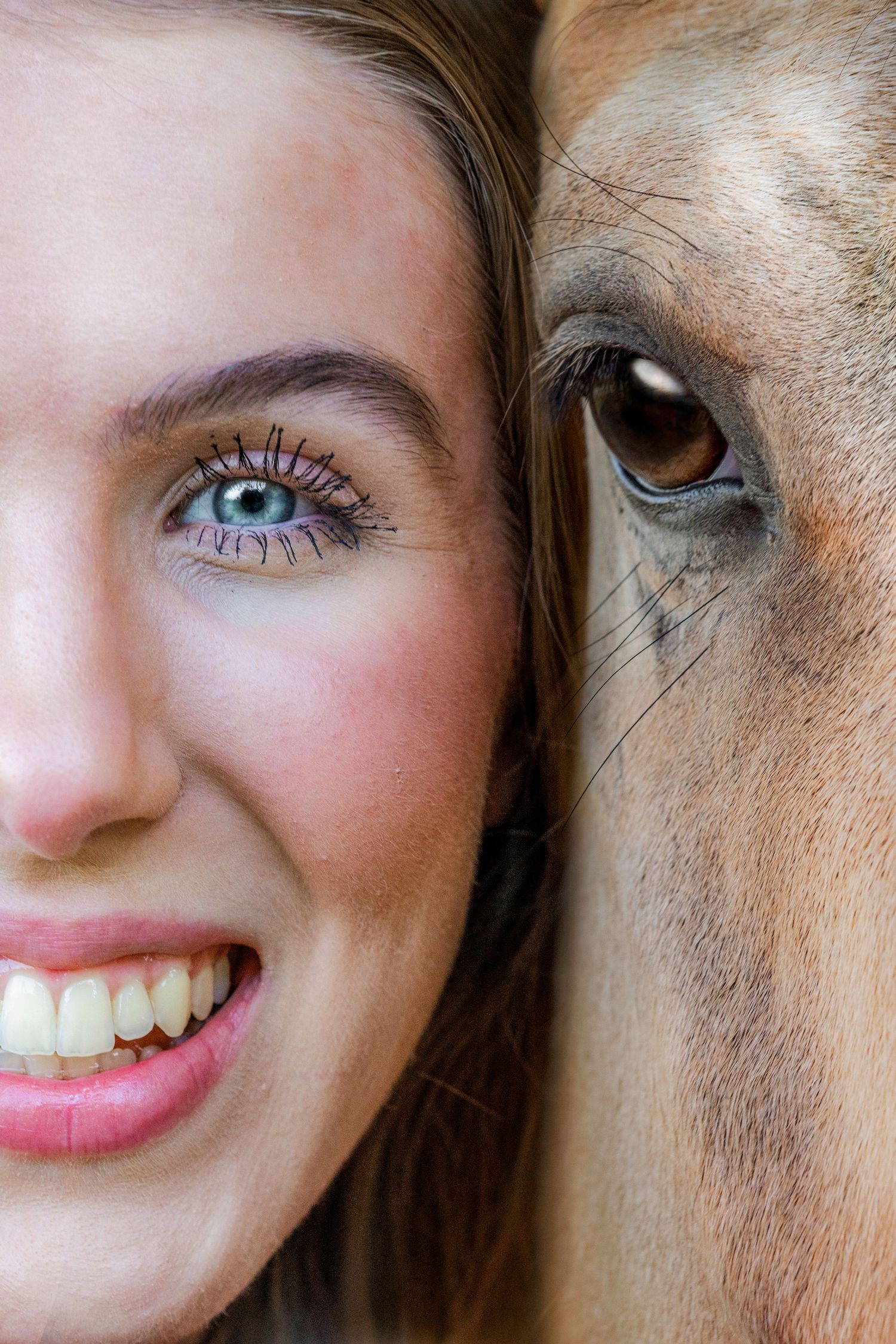 Creative split close-up portrait of smiling blue-eyed woman beside a brown horse eye.