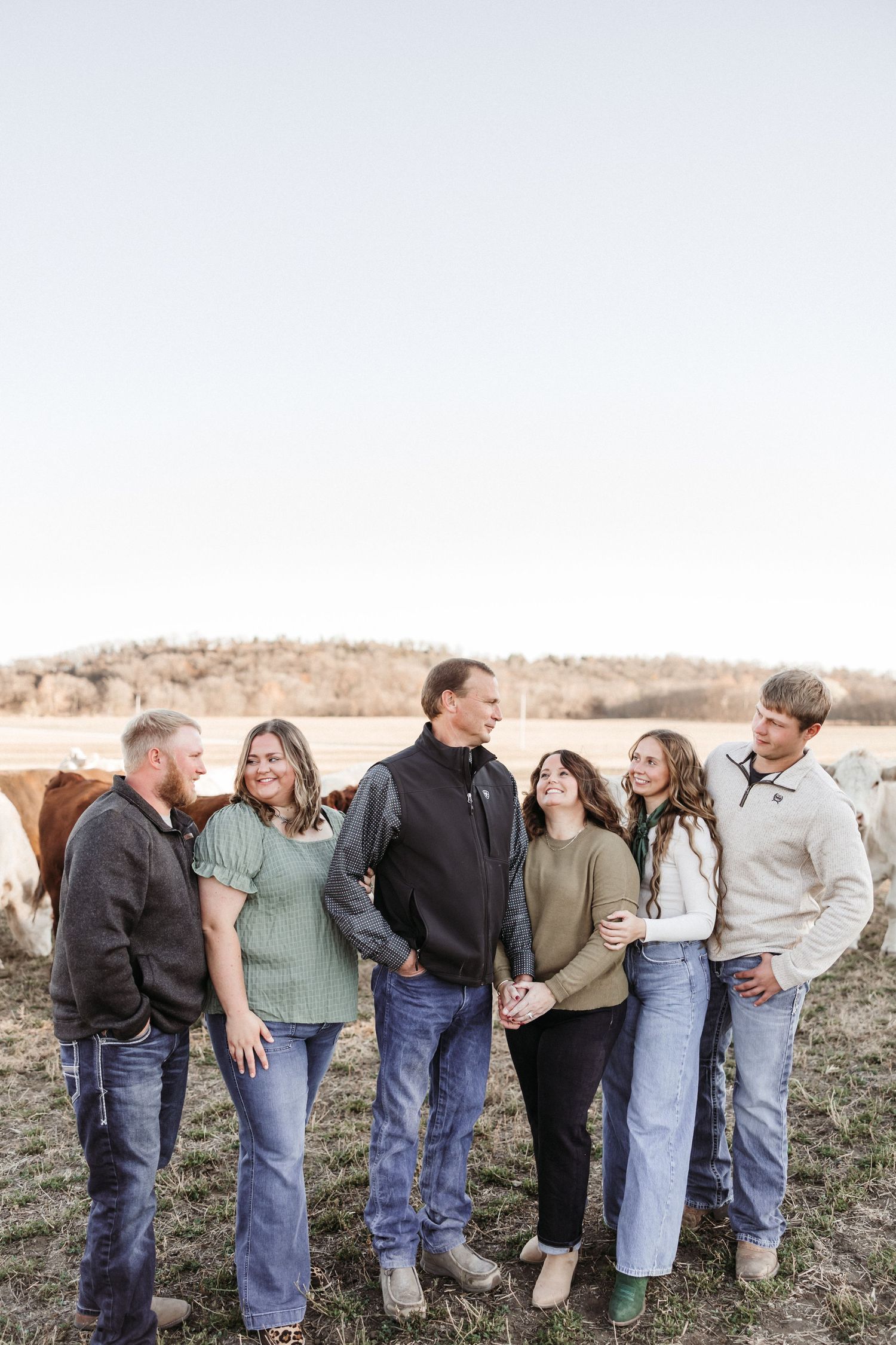 Casual family portrait with everyone leaning on each other in rustic field setting.
