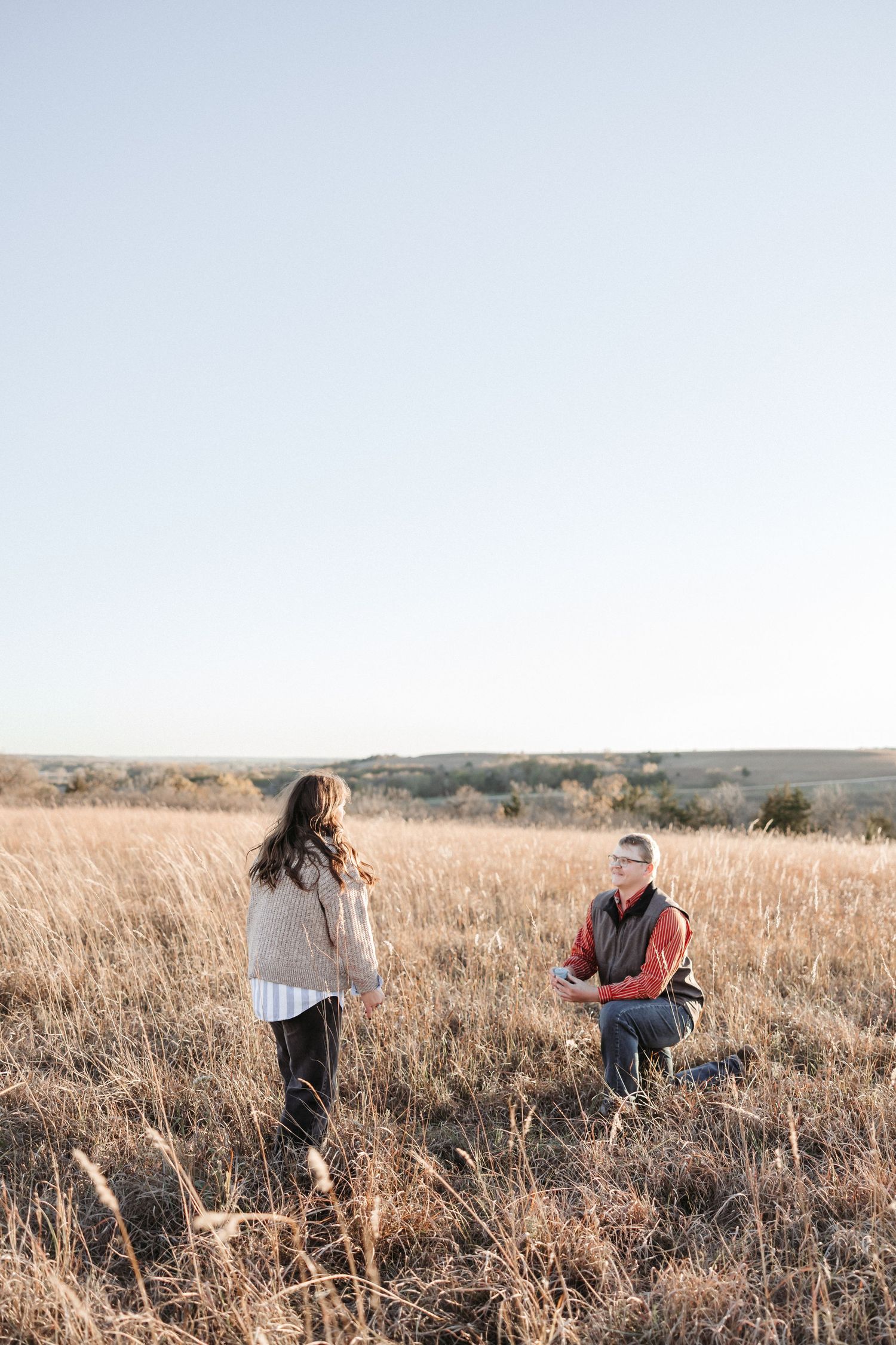 Two people share a special moment in a golden field during sunset.