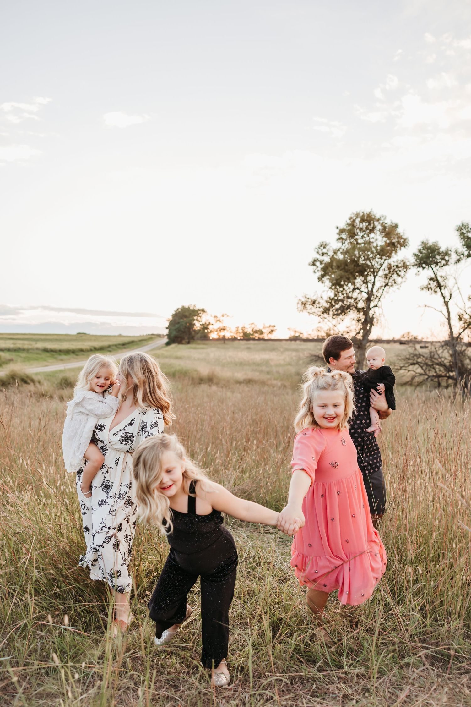Children playing and running through tall grass in a field during sunset.