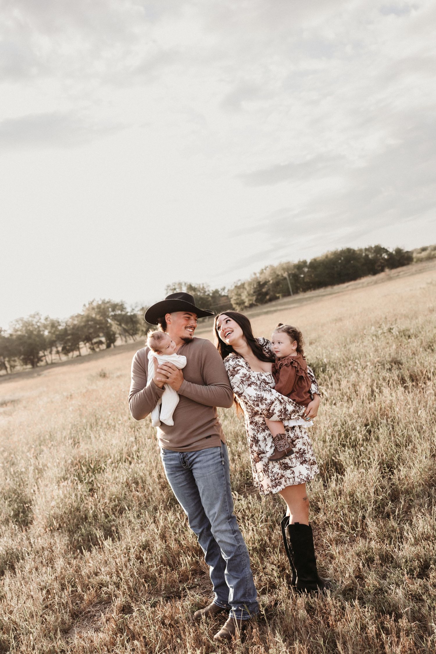 A couple shares a romantic moment in a golden field at sunset.