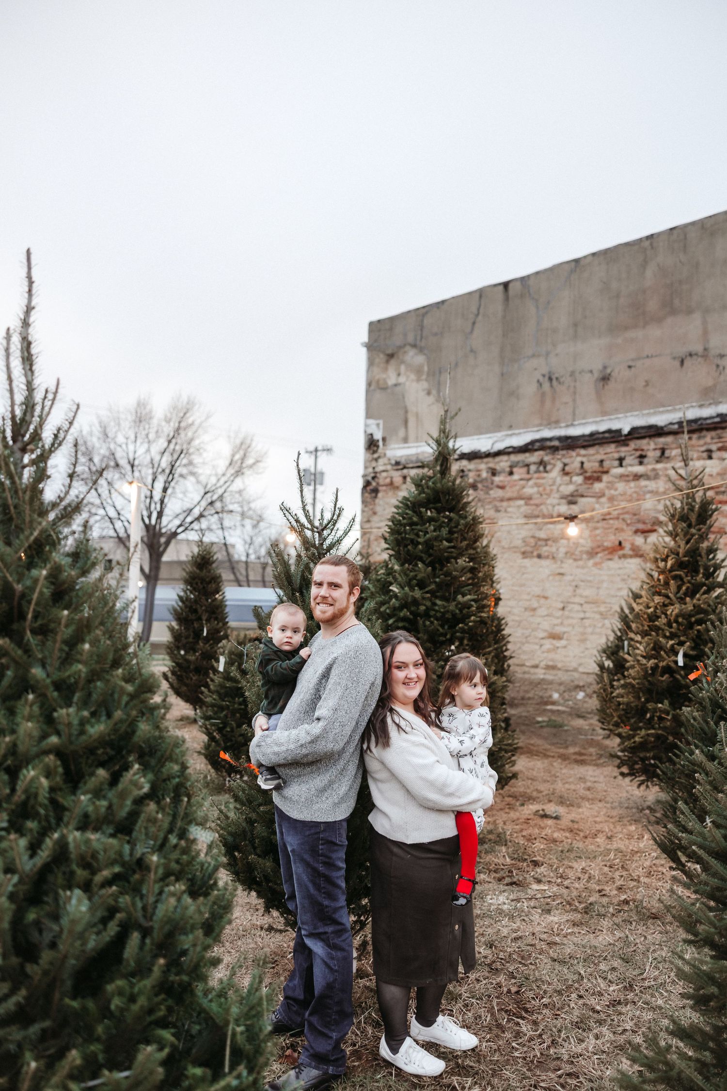 Candid family moments captured near Christmas trees.