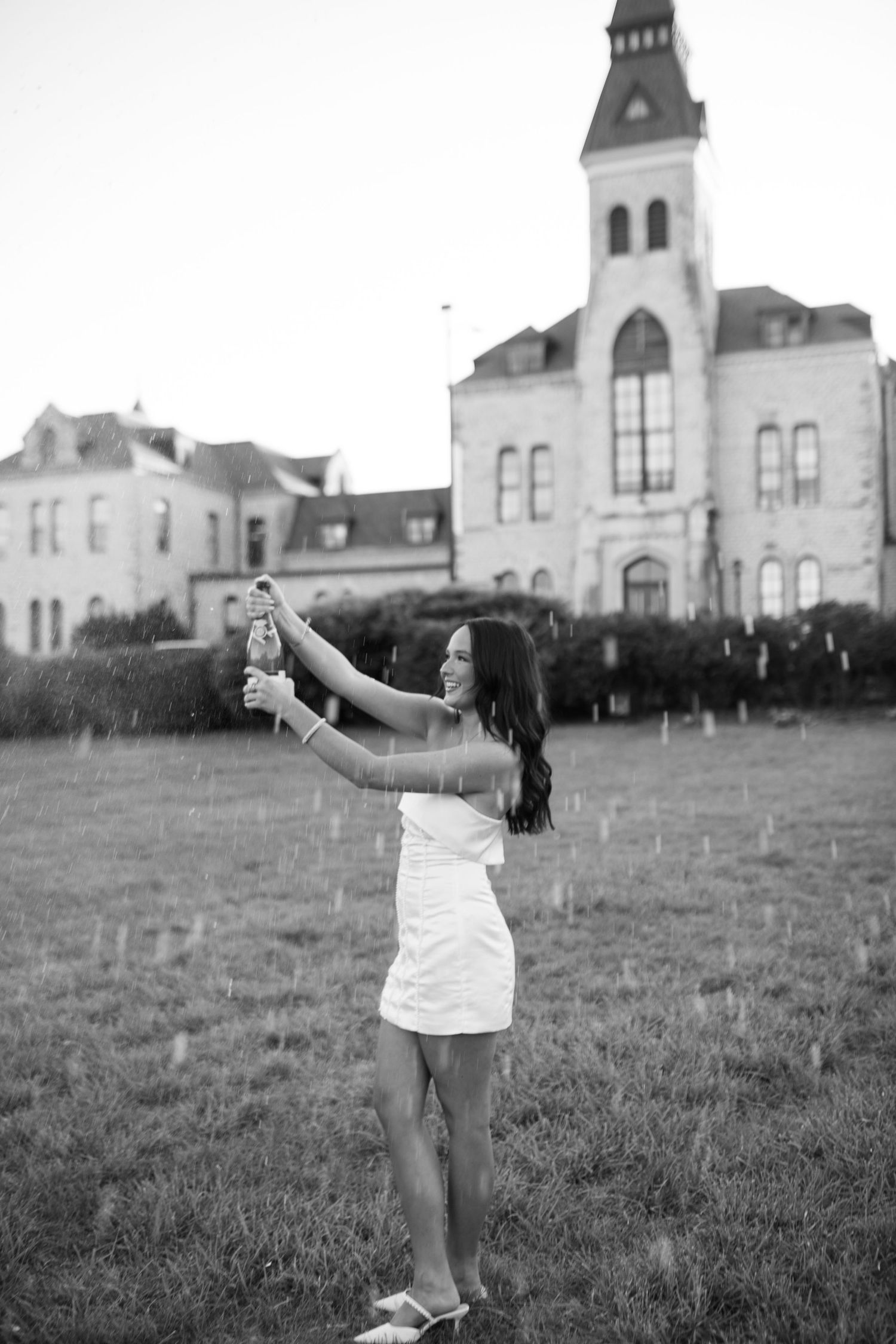 Black and white photos of graduate with champagne in front of a historic building backdrop.
