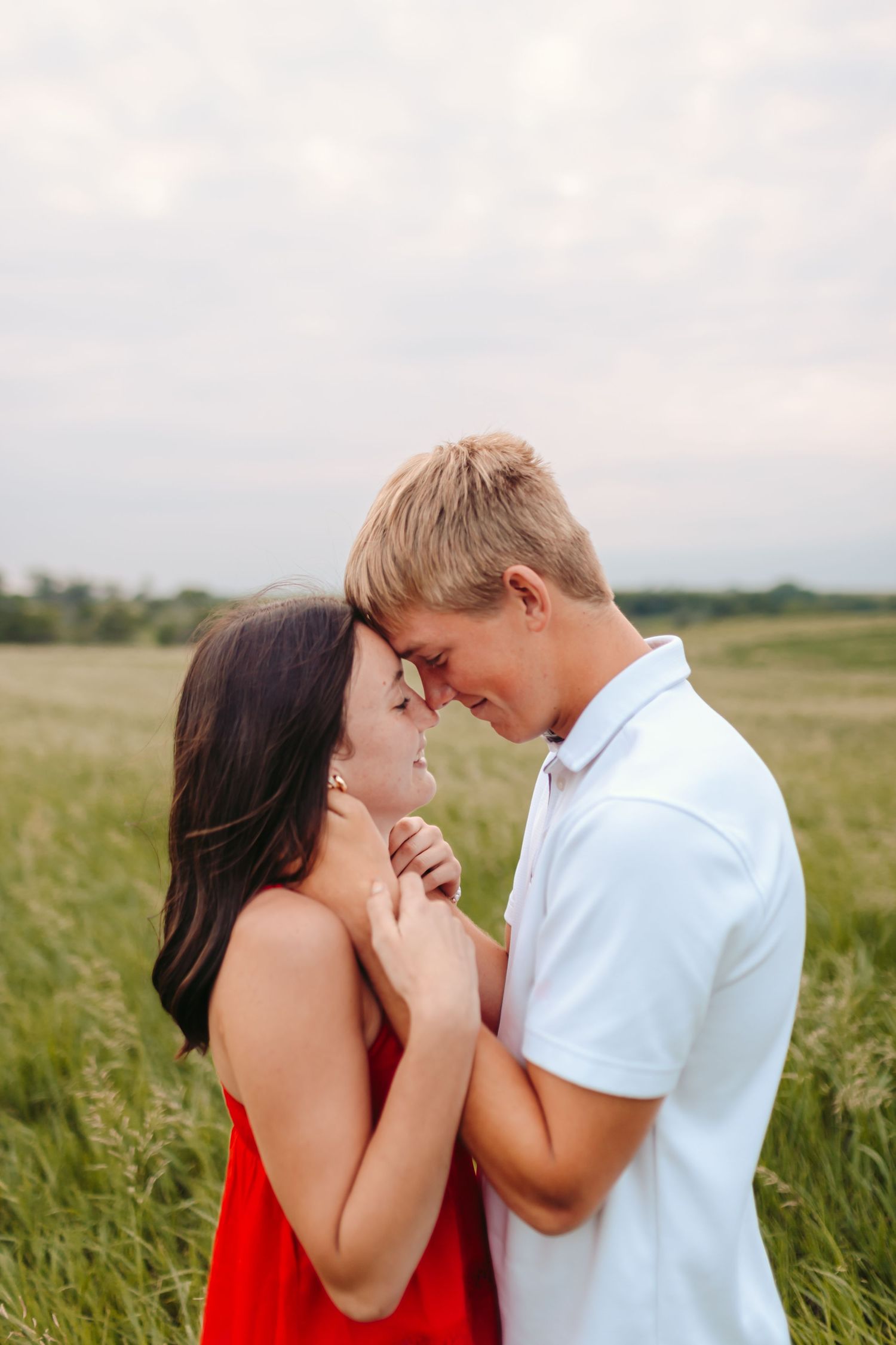 Couple sharing a tender moment while standing in a field of tall grass.