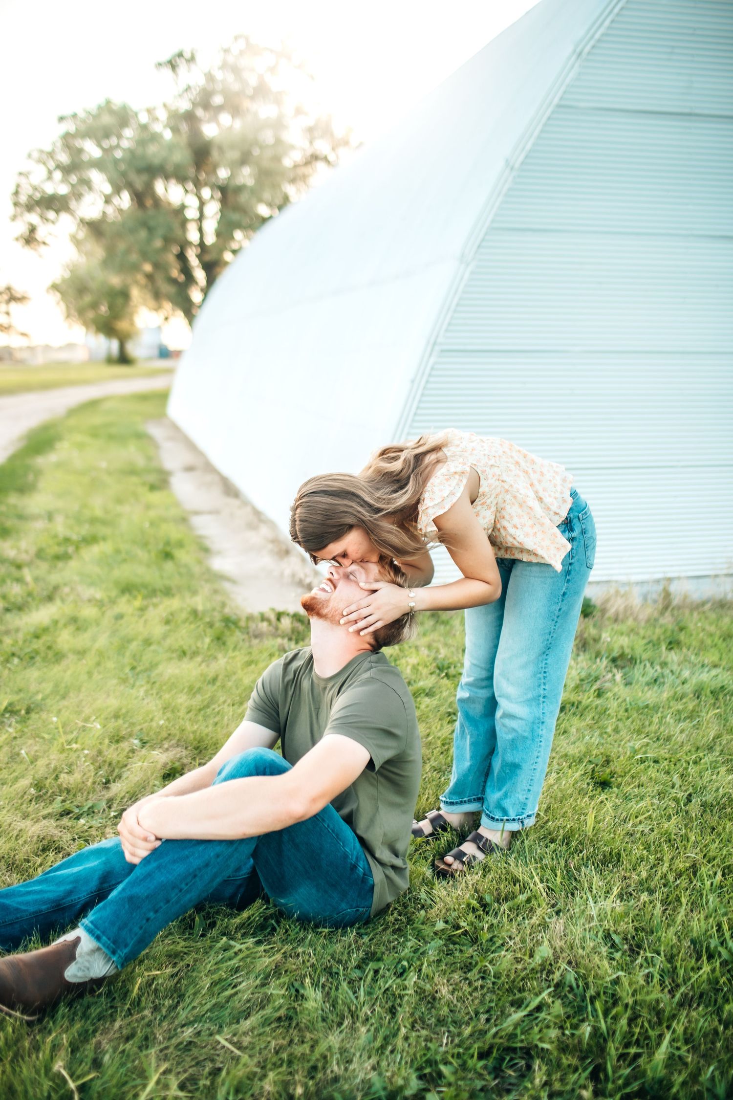 A romantic moment captured between a couple on grass near a building.