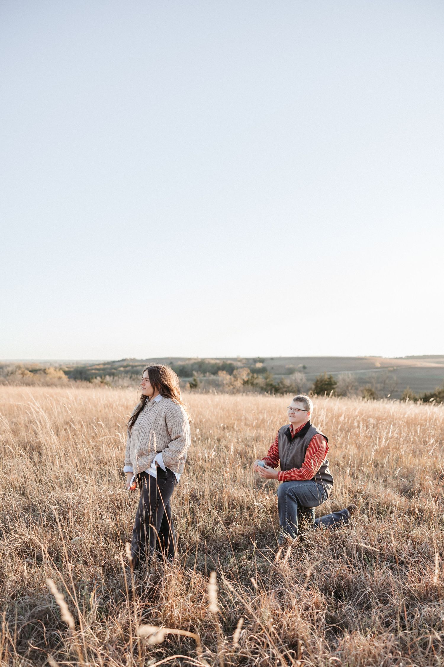 A couple shares a meaningful moment in a sunlit prairie field.