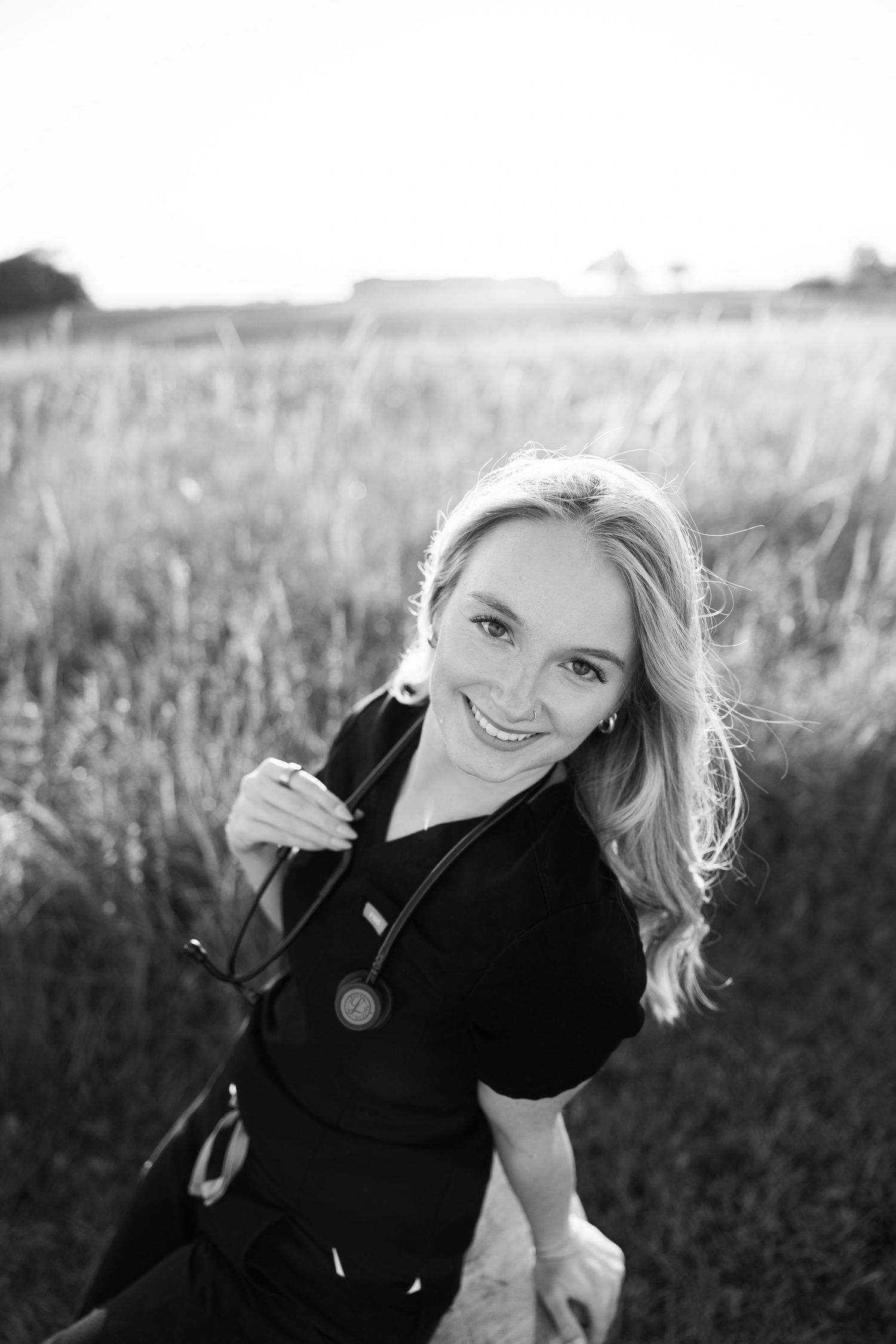 Black and white outdoor portraits in a sunlit field with natural poses.