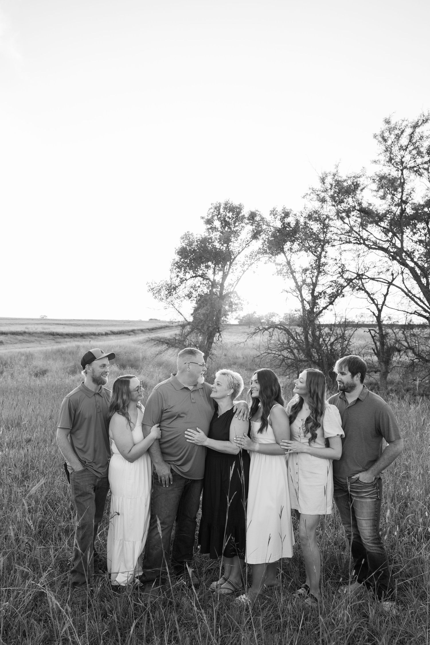 Group portrait of people standing together in styled clothing against a rural landscape.