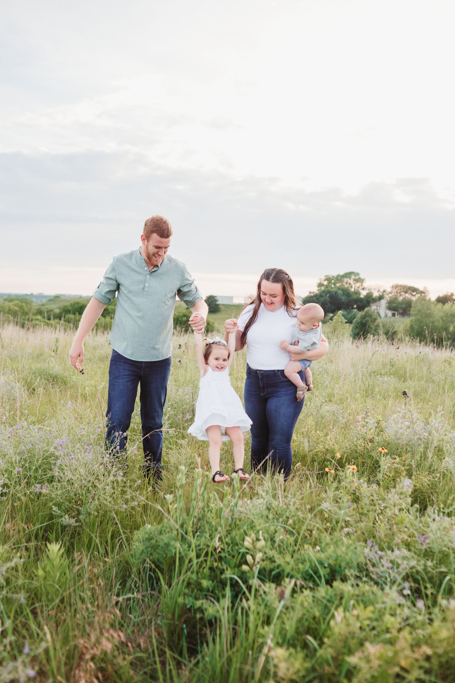 A joyful family walking and playing together through a wildflower meadow on a sunny afternoon.