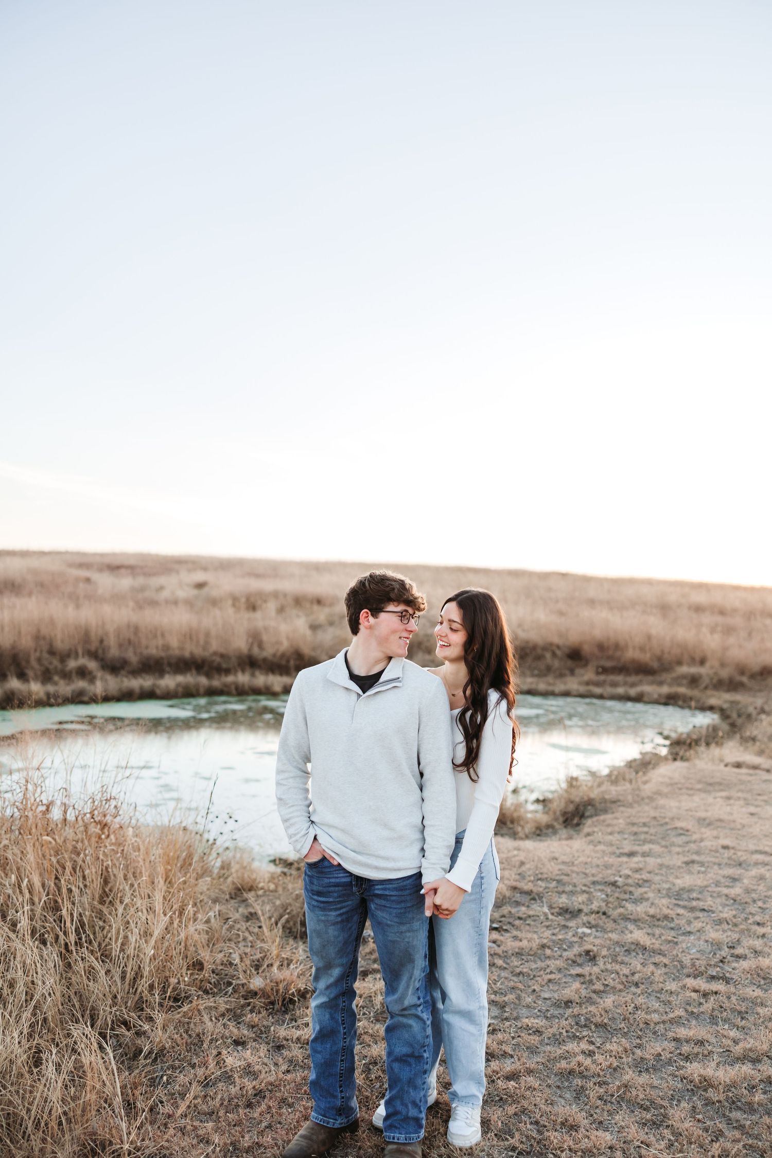A loving couple sharing an intimate moment along a pond during golden hour.