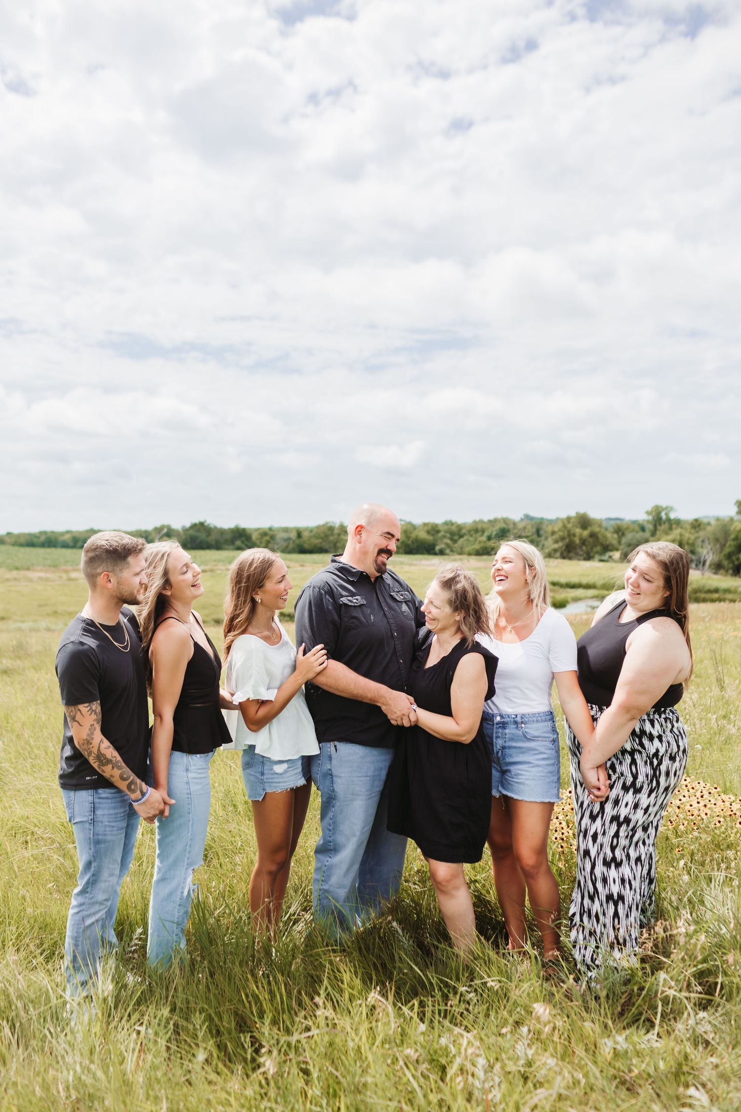 A family in a fun group pose in a sunny meadow.