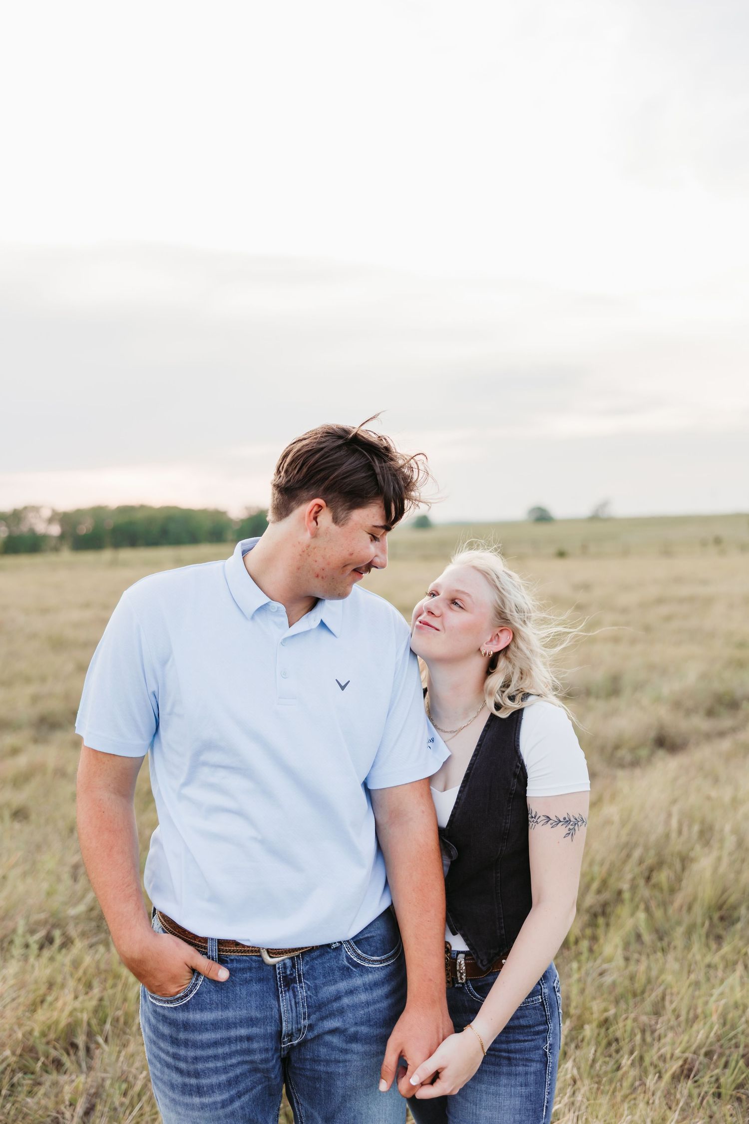 A couple shares a joyful moment together in a rustic prairie setting.